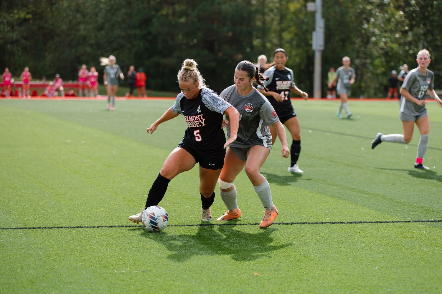 Intense soccer game action with players competing for the ball on grass field.