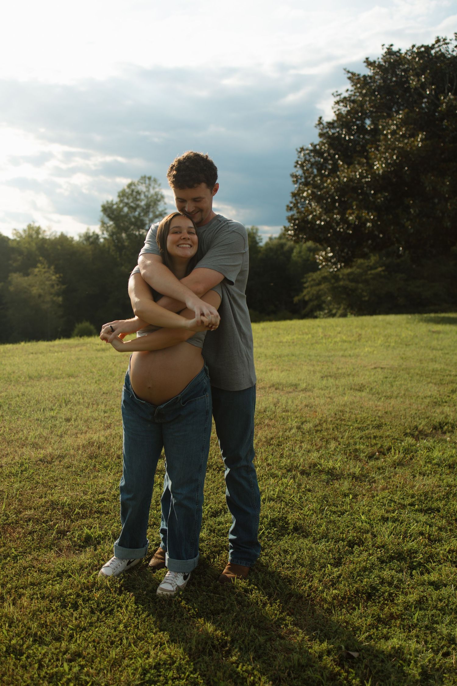 Couple embracing in golden sunlight on grassy field.