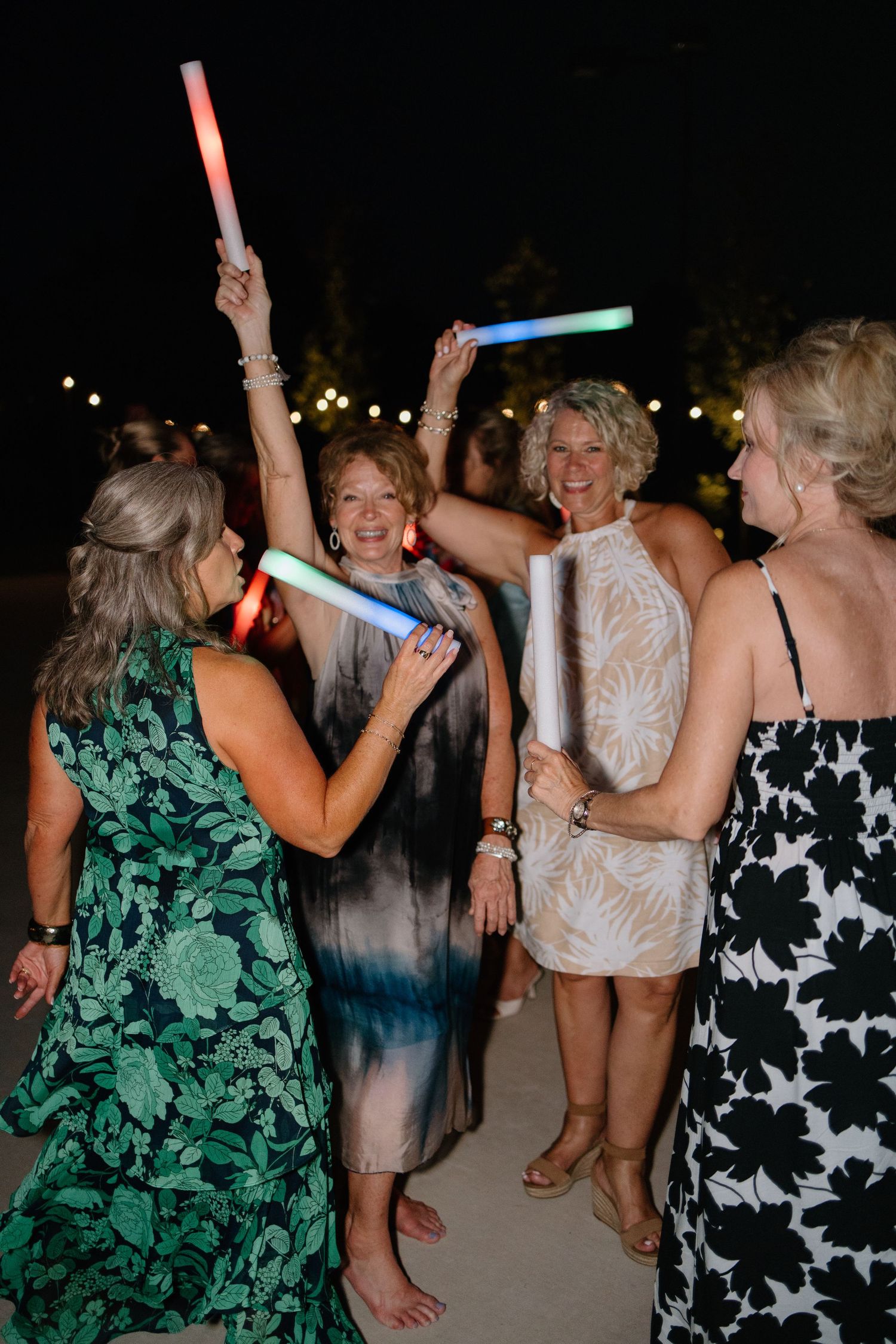 A group of party guests dancing and waving light sticks on a dark dance floor during a celebration.