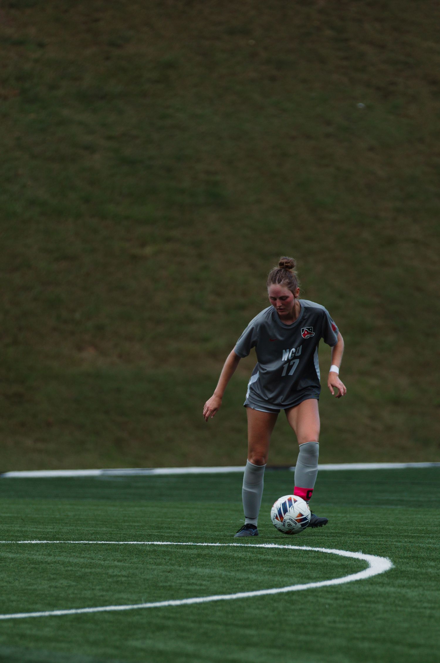 Soccer player dribbling ball along curved white line on turf field.