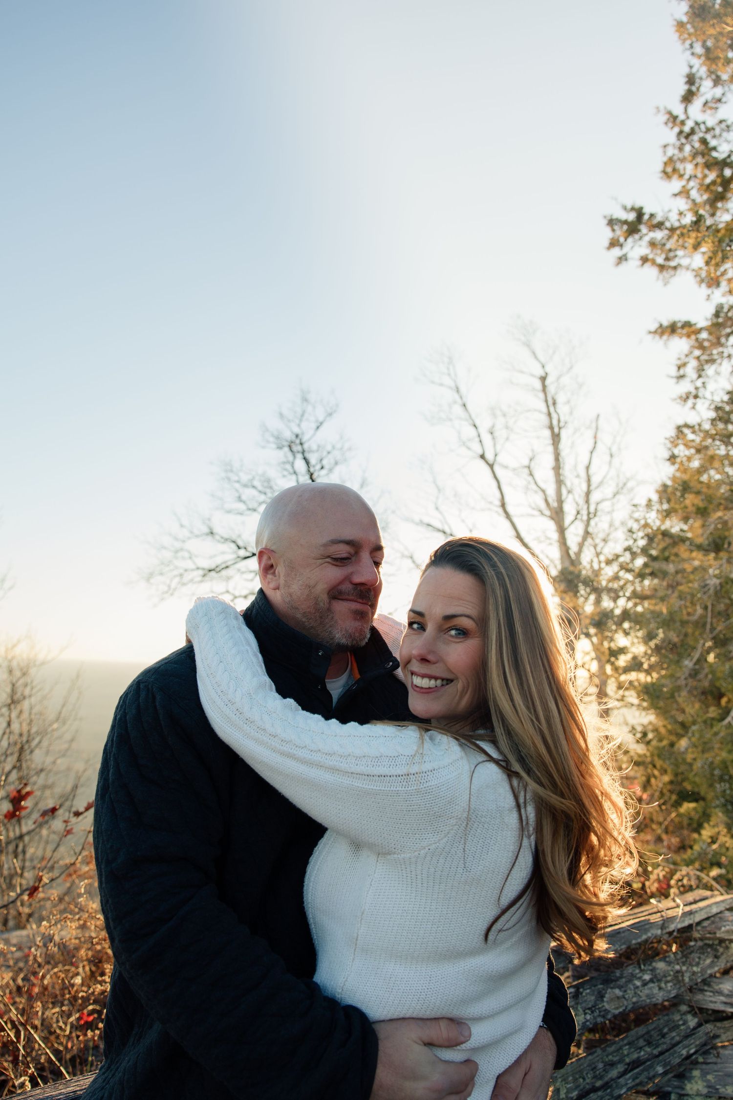 A couple in winter clothing sharing a joyful embrace outdoors during golden hour.