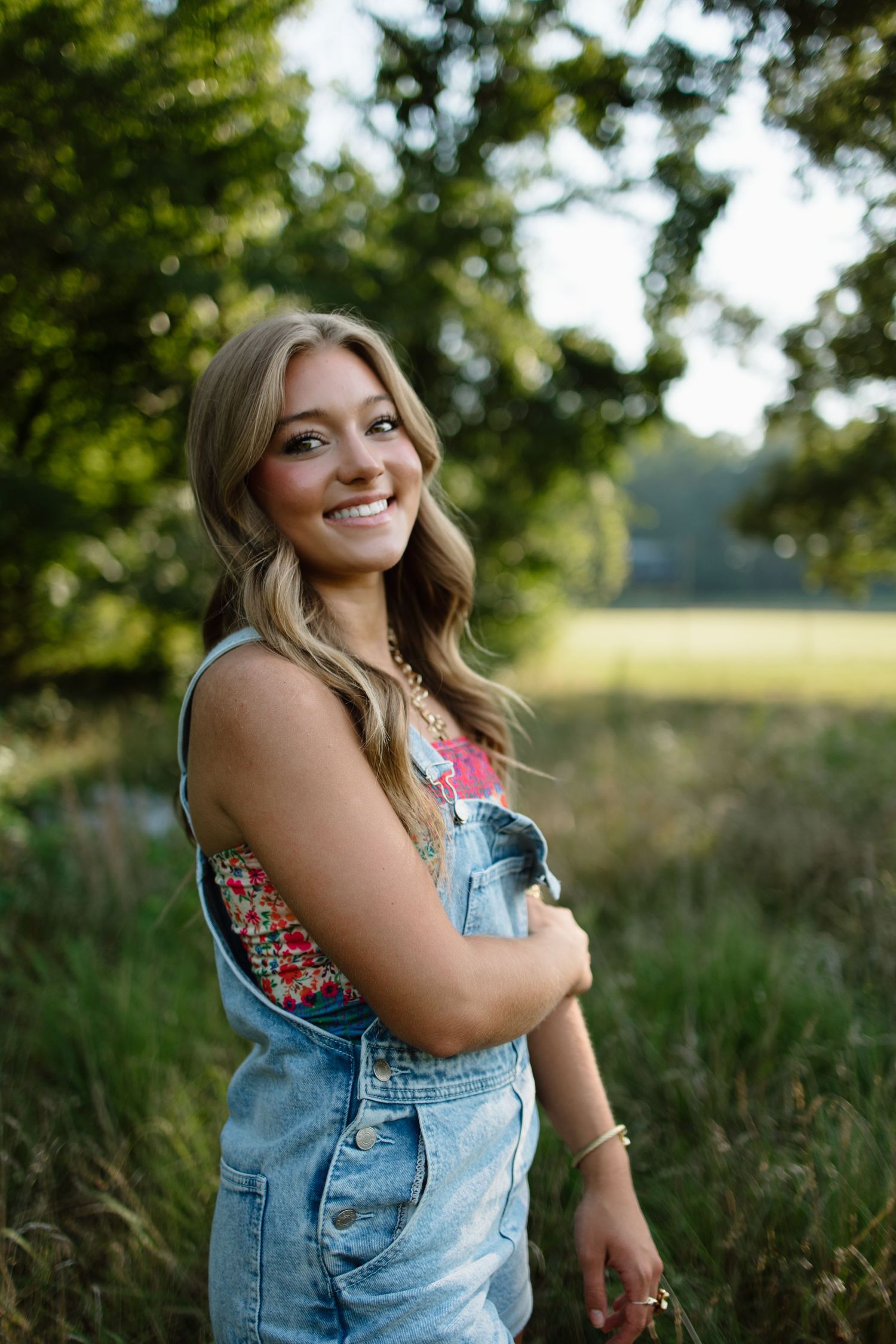 Summer portrait in overalls against natural field backdrop.