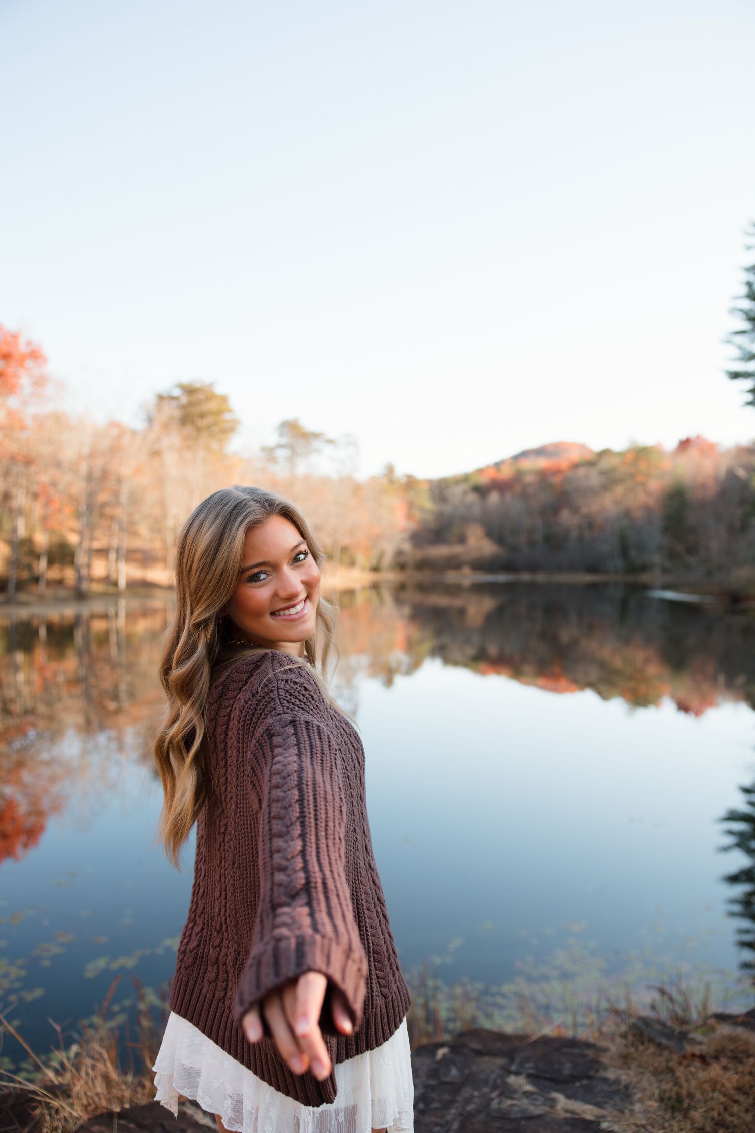 Scenic autumn lakeside view with reflective water and fall foliage.