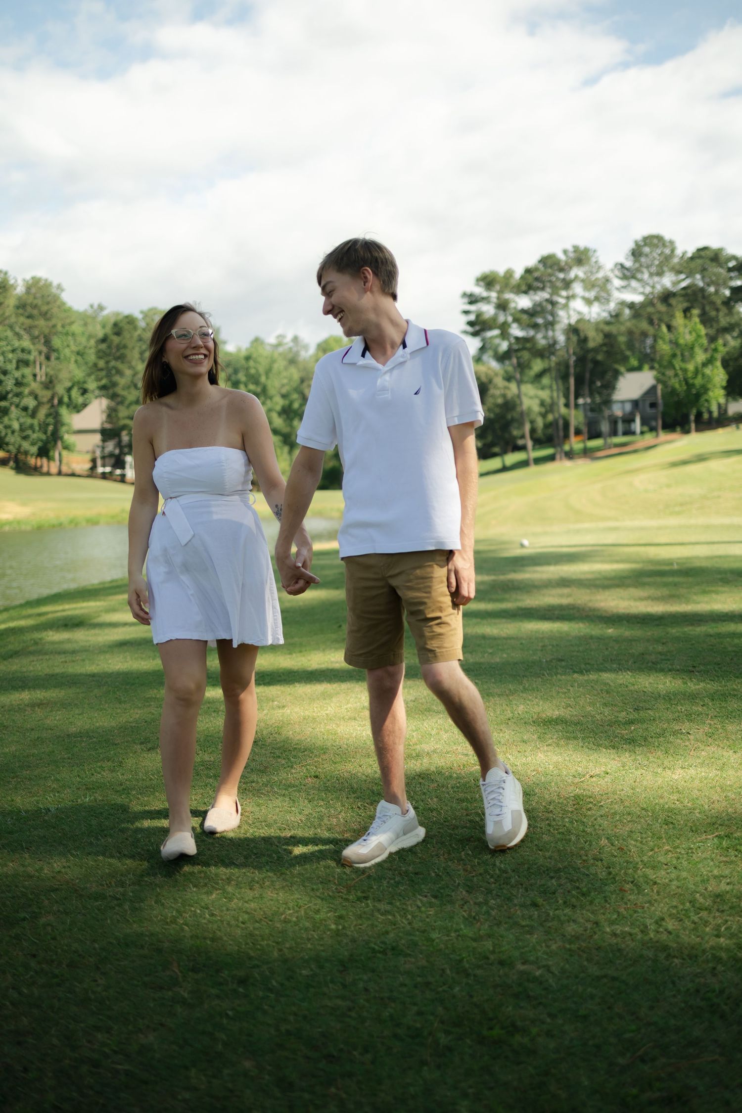 Playful couple walking together on grassy field during photo session.
