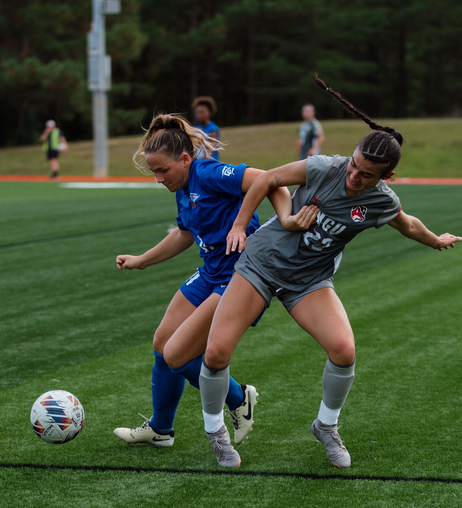 Soccer players compete for ball control during  match on turf field.