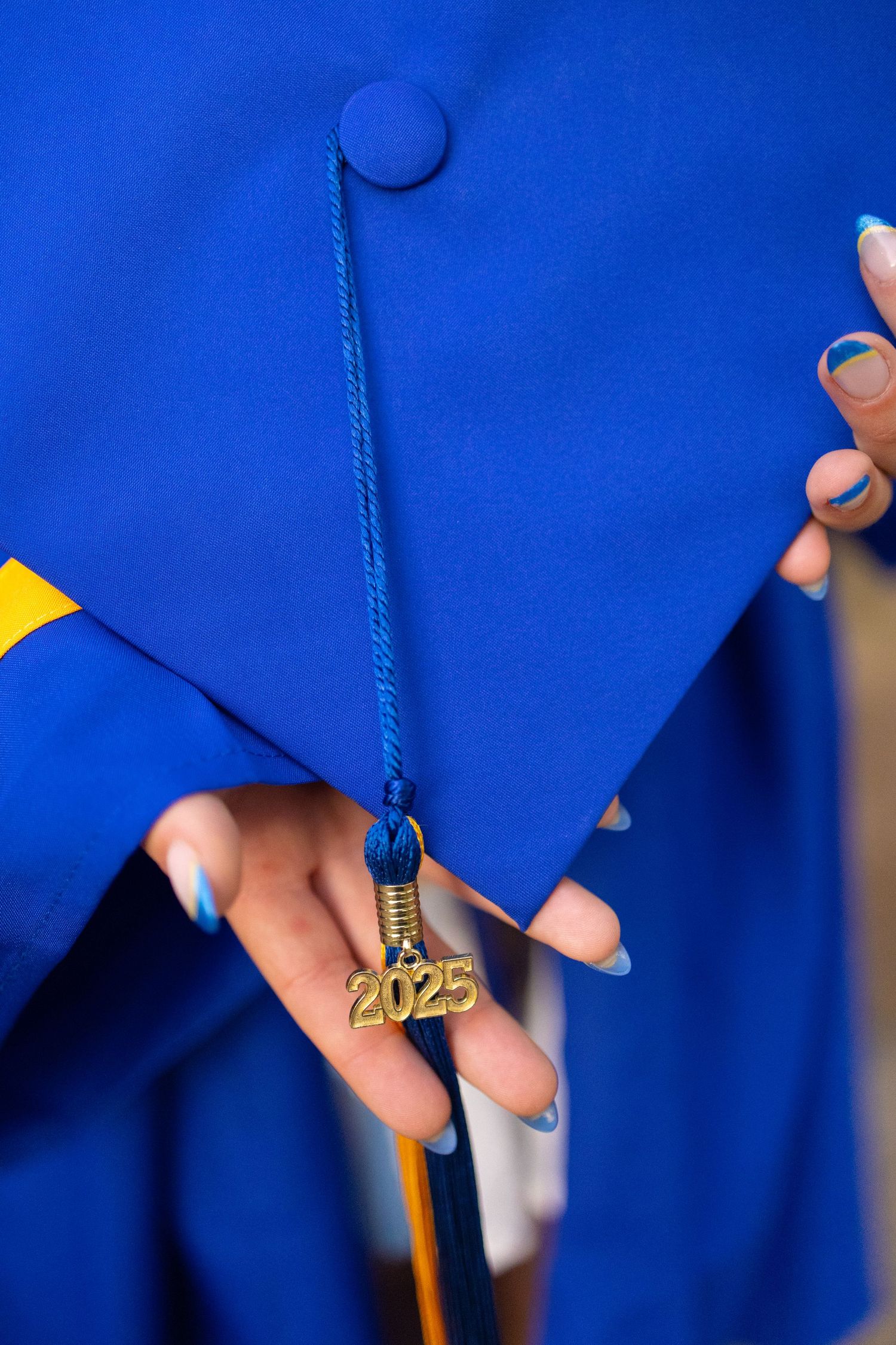 Detail shots of blue graduation gown with gold tassel decorations.