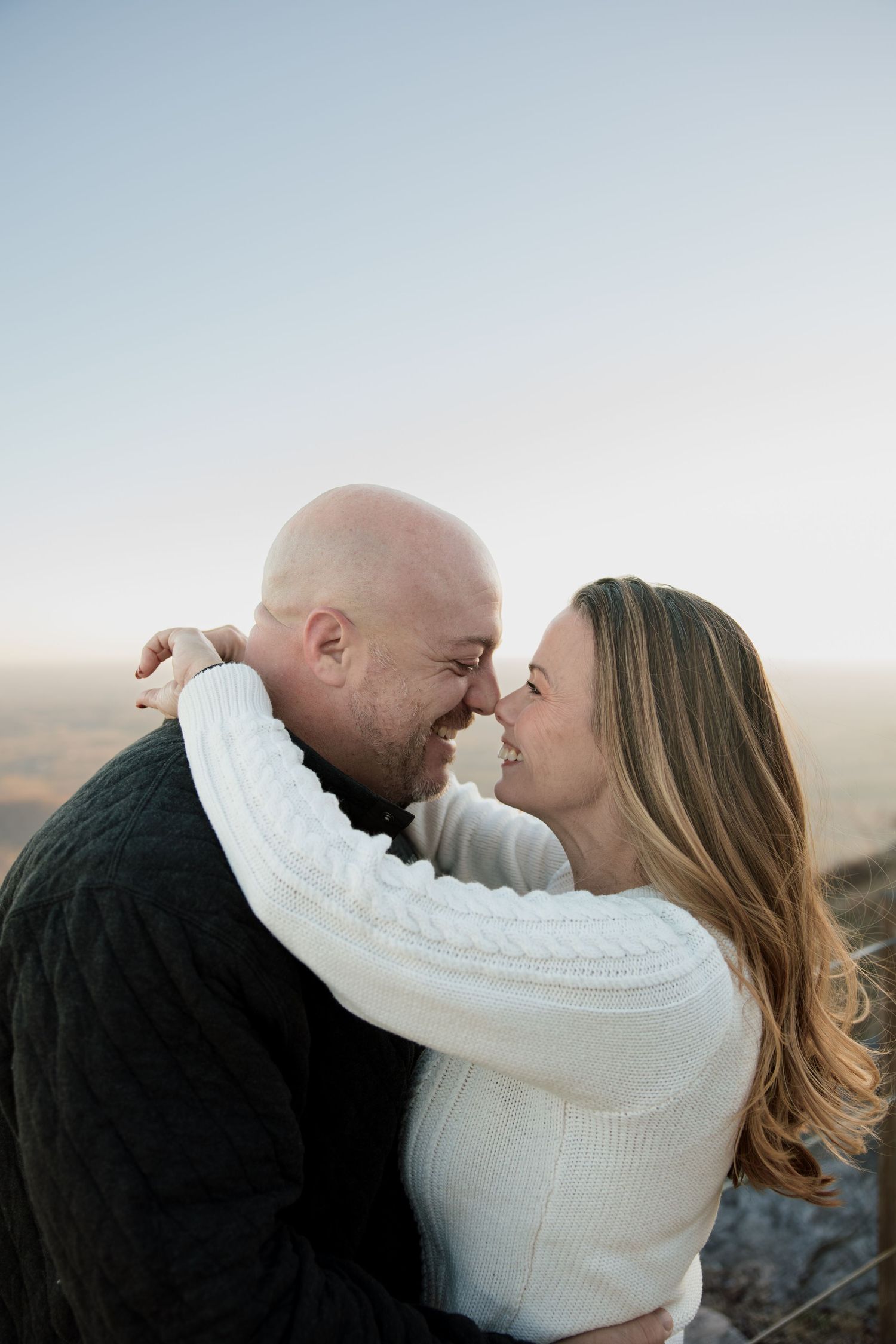 A romantic couple embraces outdoors at sunset wearing black and white sweaters in a series of candid moments.