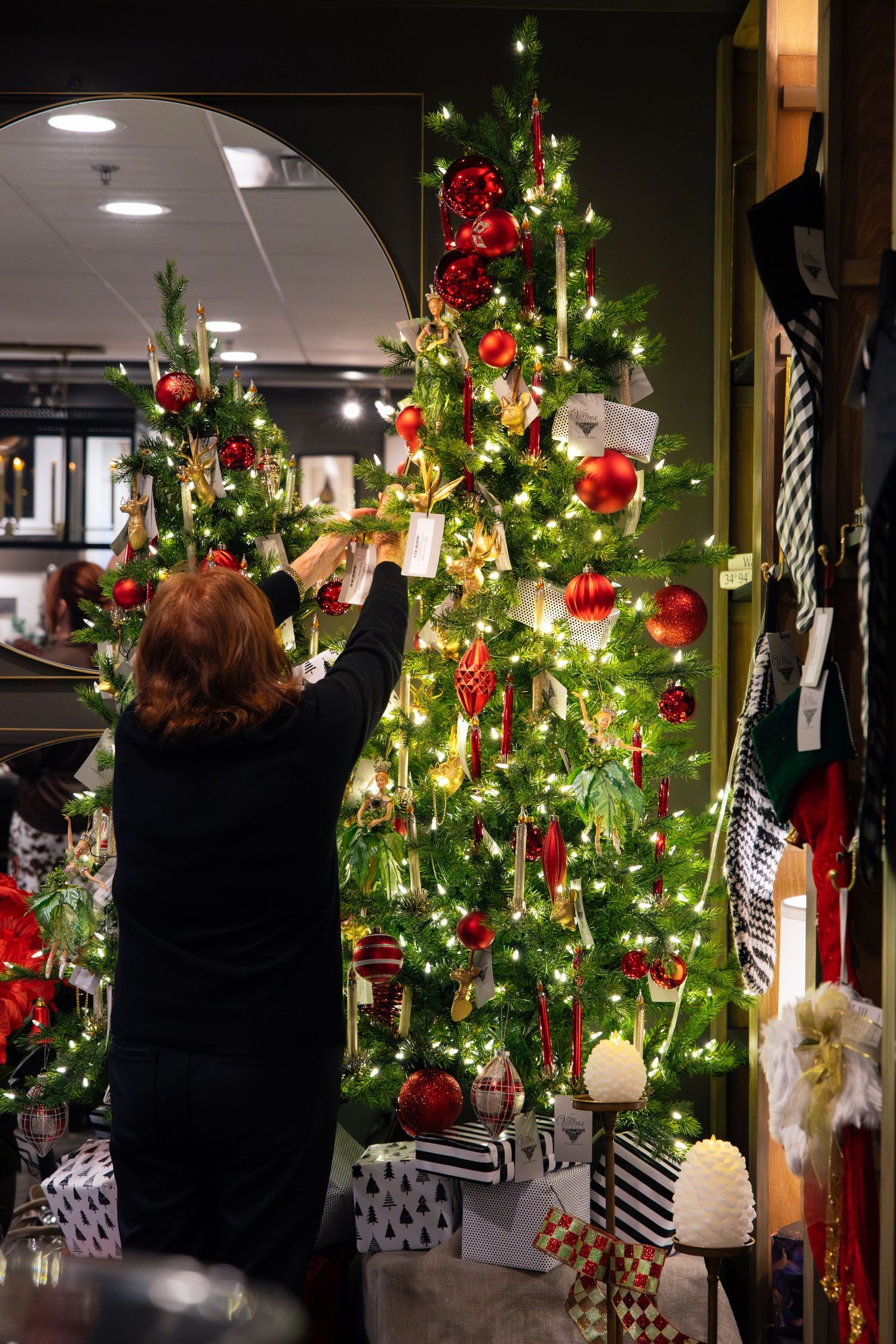 Row of illuminated Christmas trees decorated with red ornaments and lights in retail space.