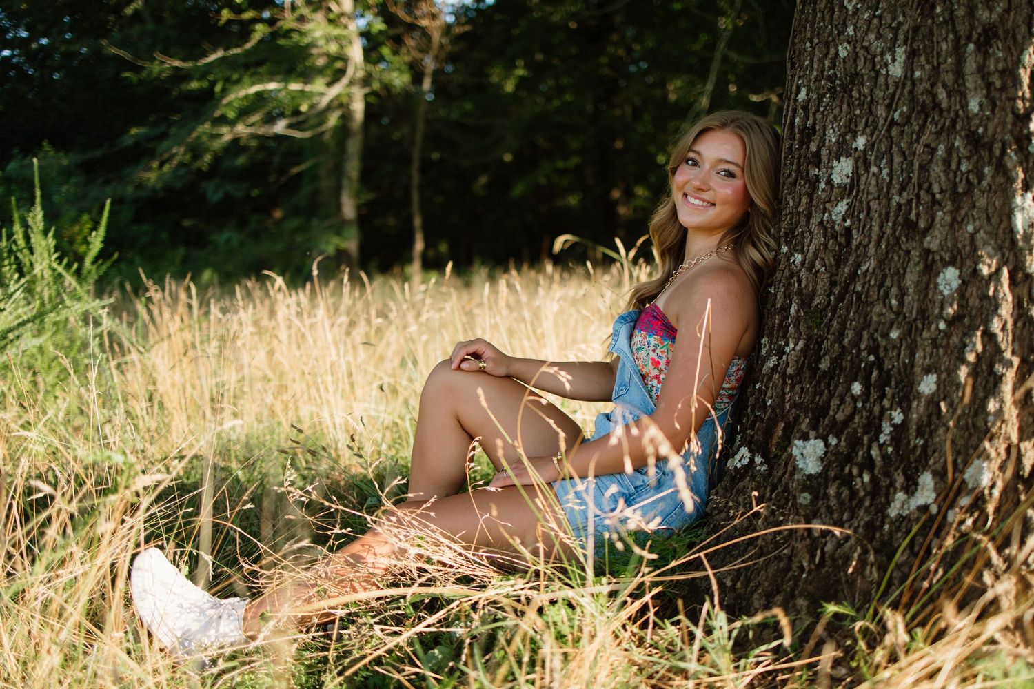 Natural outdoor portrait session against tree trunk in dappled sunlight.