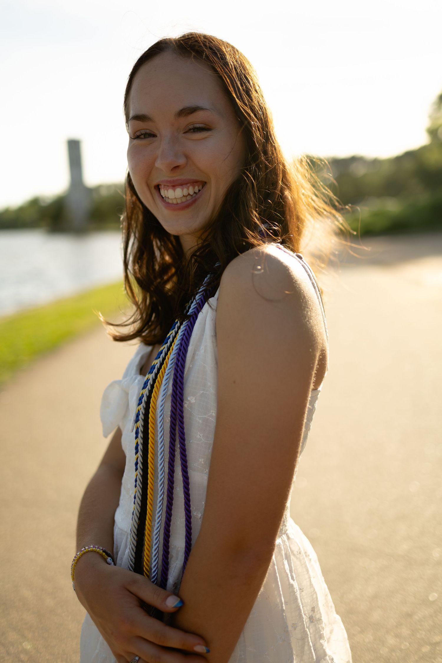 Graduation portrait with decorative tassels in warm sunlight.