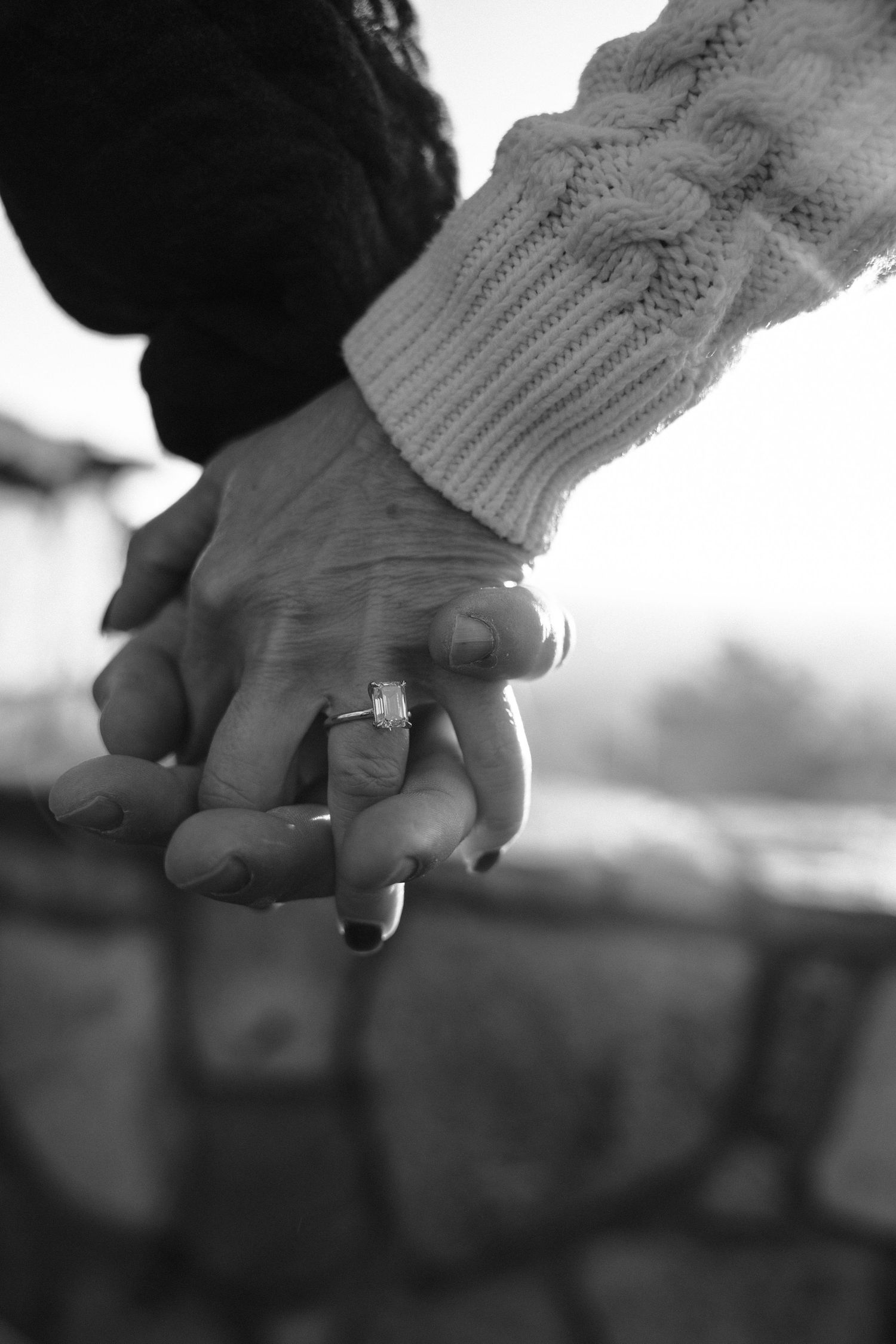 Close-up sequence of hands holding an engagement ring in black and white.