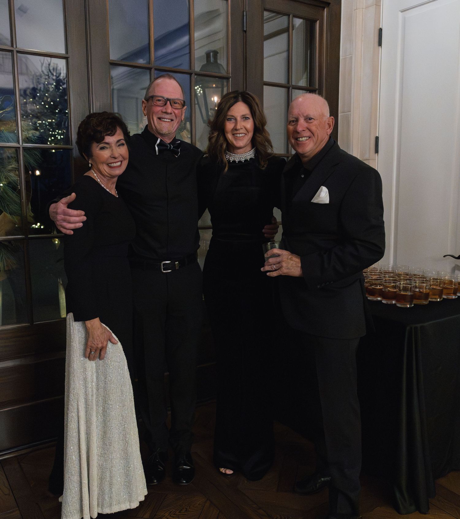 Group gathered for formal evening event wearing black attire in elegant interior setting.