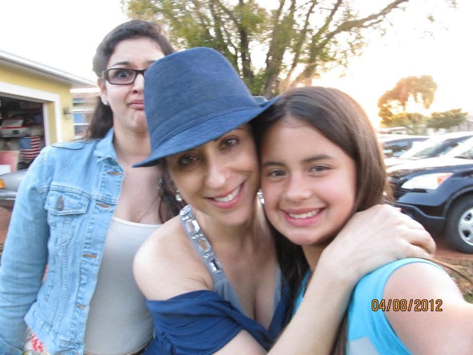 Two girls and a woman smiling and hugging outdoors in a parking lot on April 8, 2012.