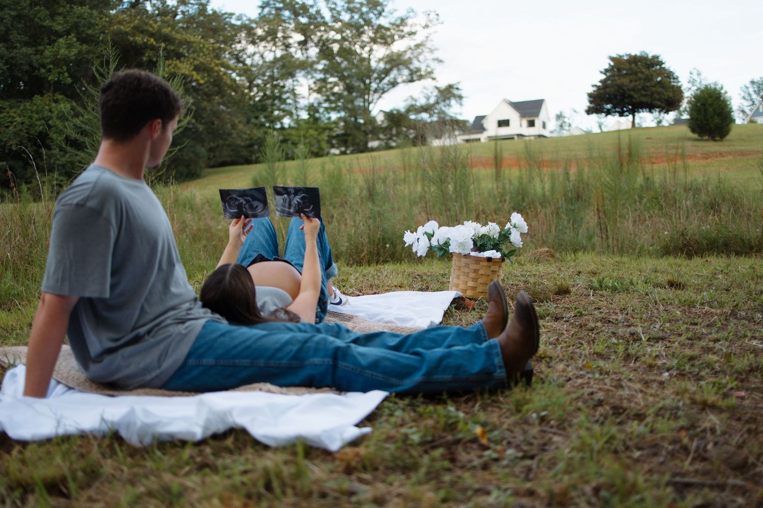 A couple lounges on a blanket in a scenic hillside field during golden hour.