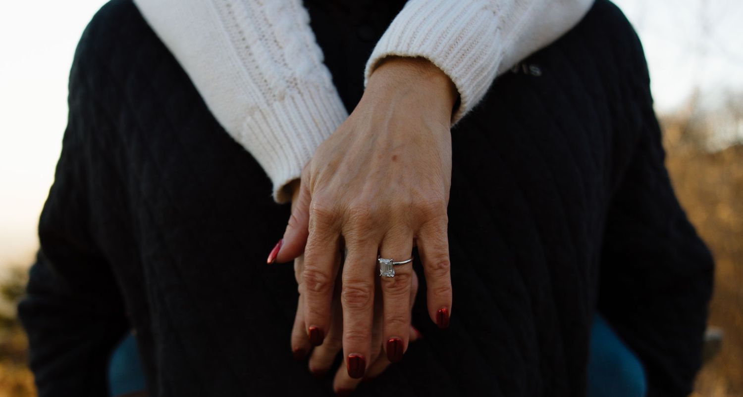 Close-up of hands touching tenderly against a dark background.