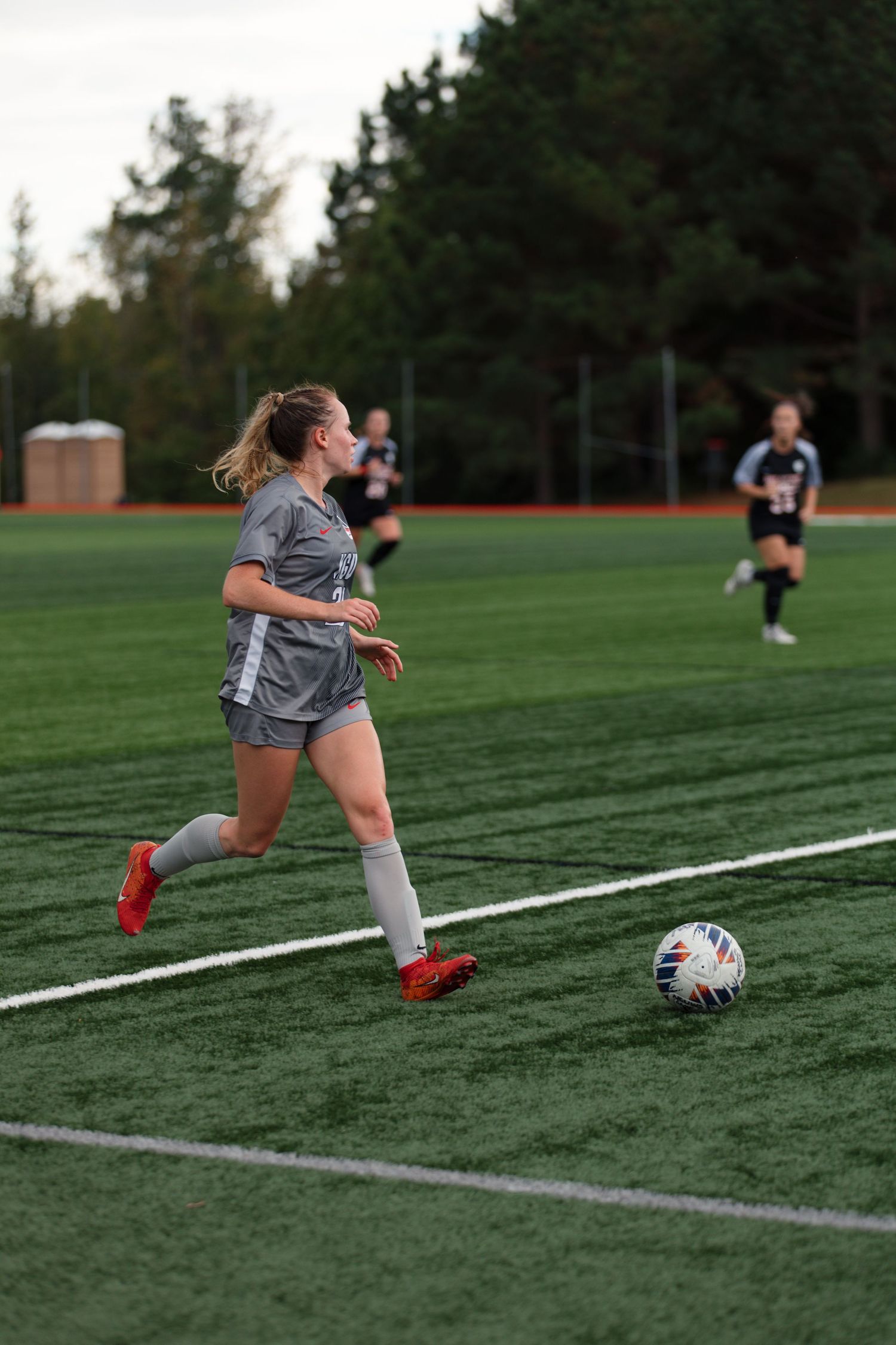Soccer player dribbling a ball along white field lines during practice.
