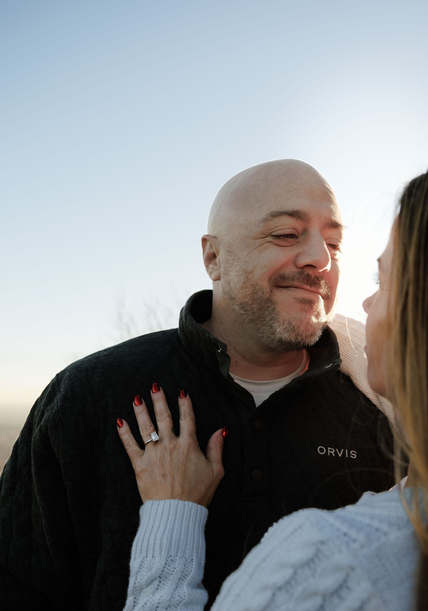Close up portrait of a couple sharing an intimate moment against a bright sky.