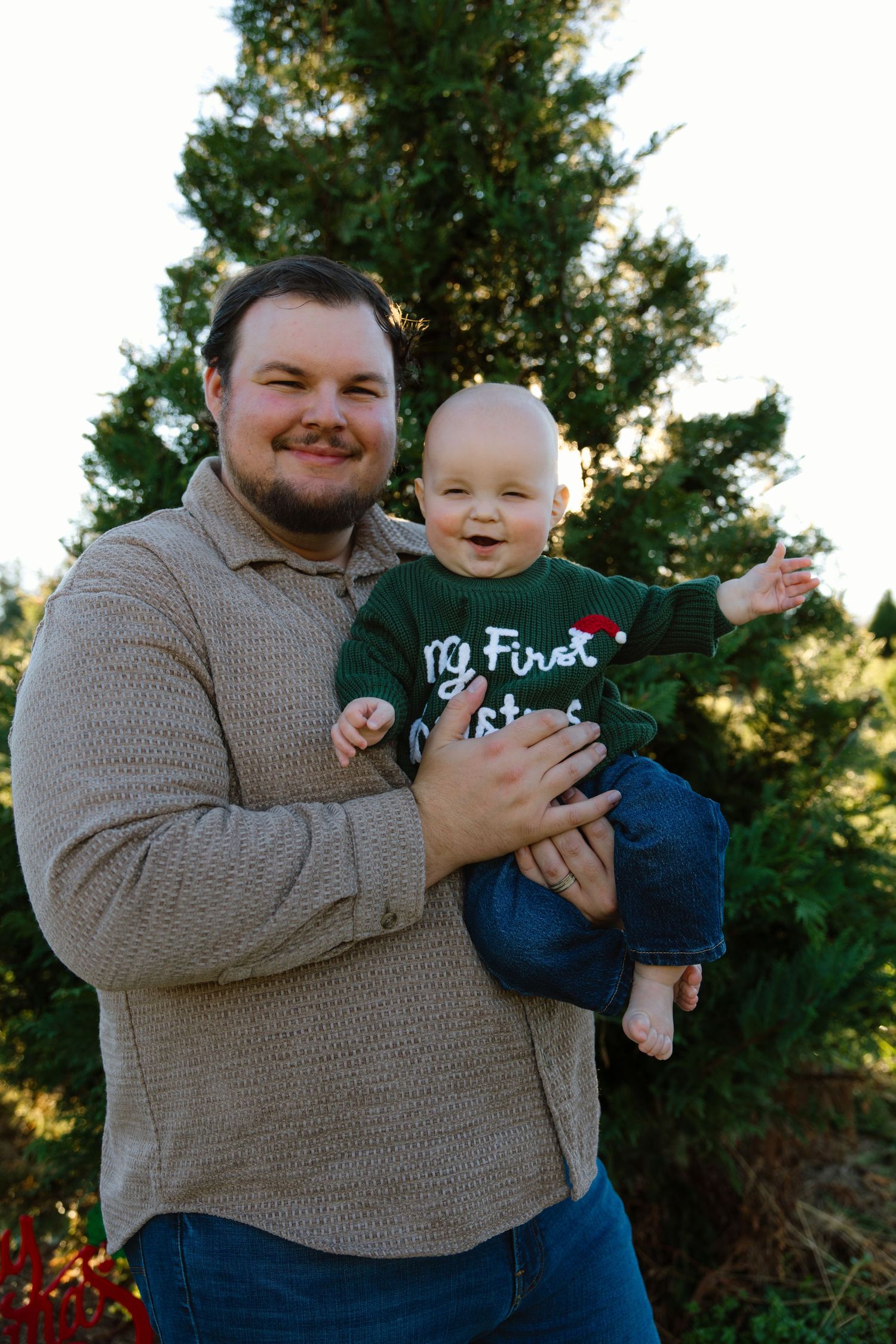 Holiday portrait in front of evergreen tree during sunset.