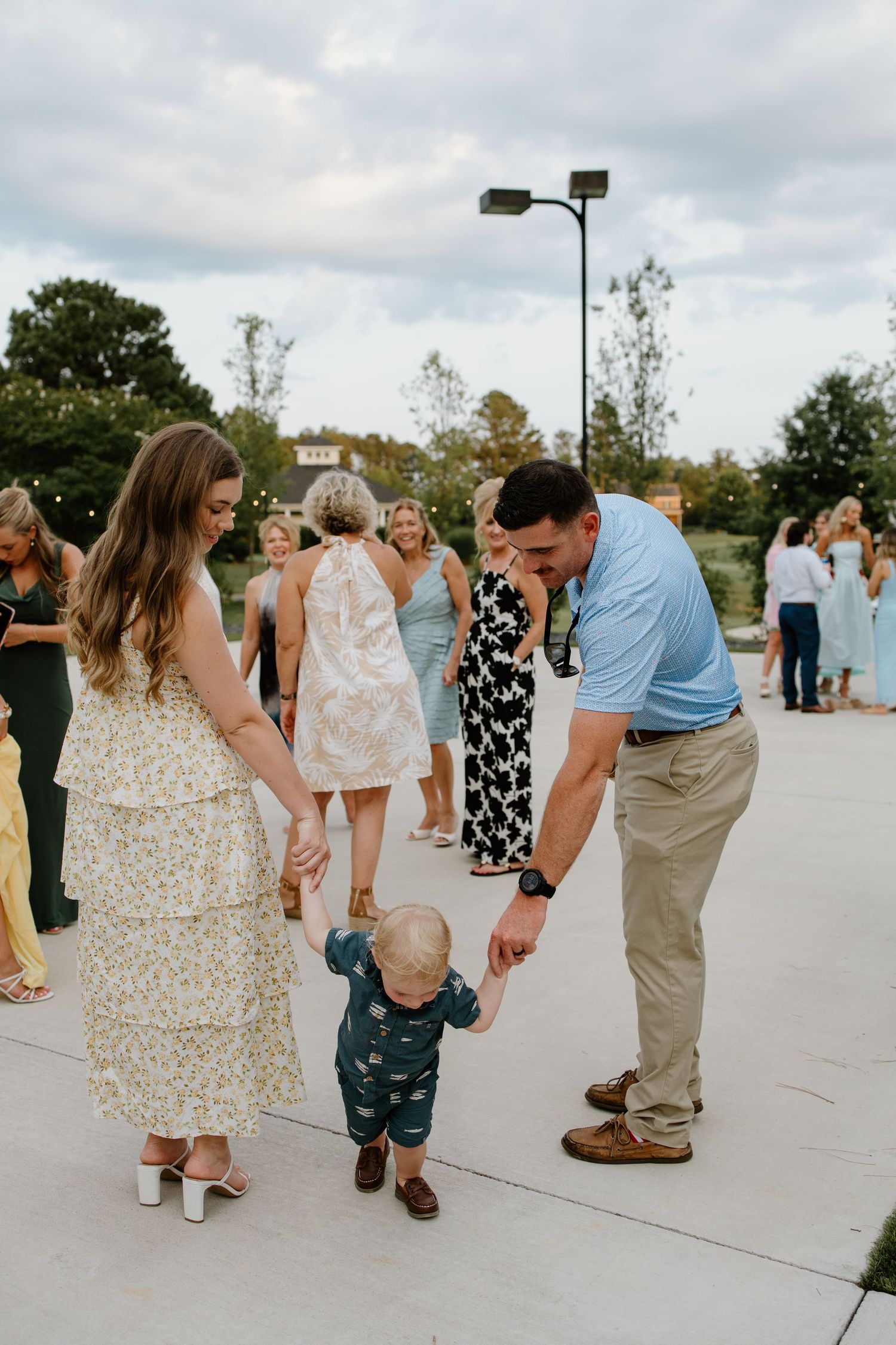 People in summer dresses and casual wear dancing and socializing at an outdoor gathering.