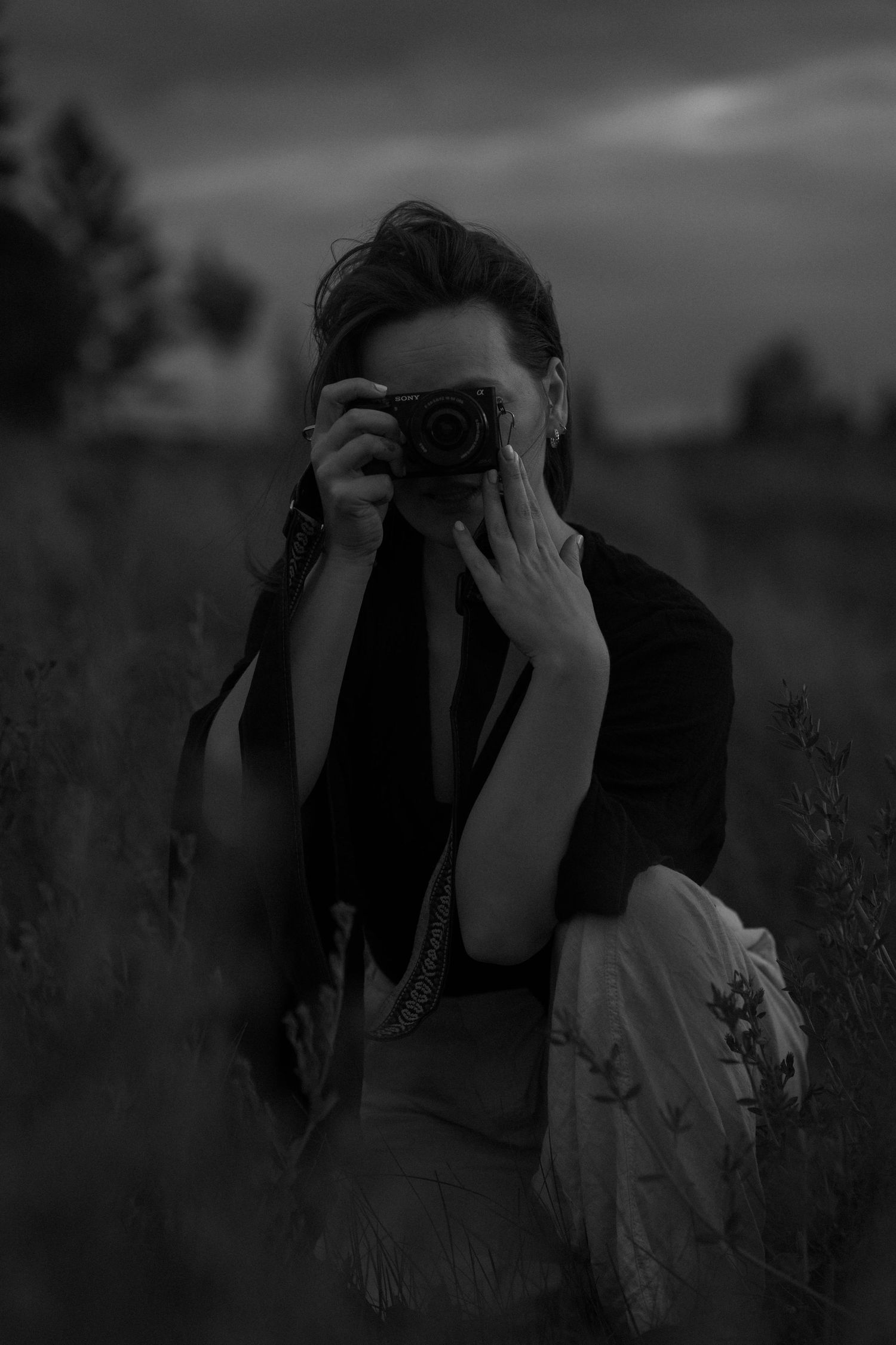 A sequence of dark monochrome images showing someone using a camera to take photographs in a natural setting.