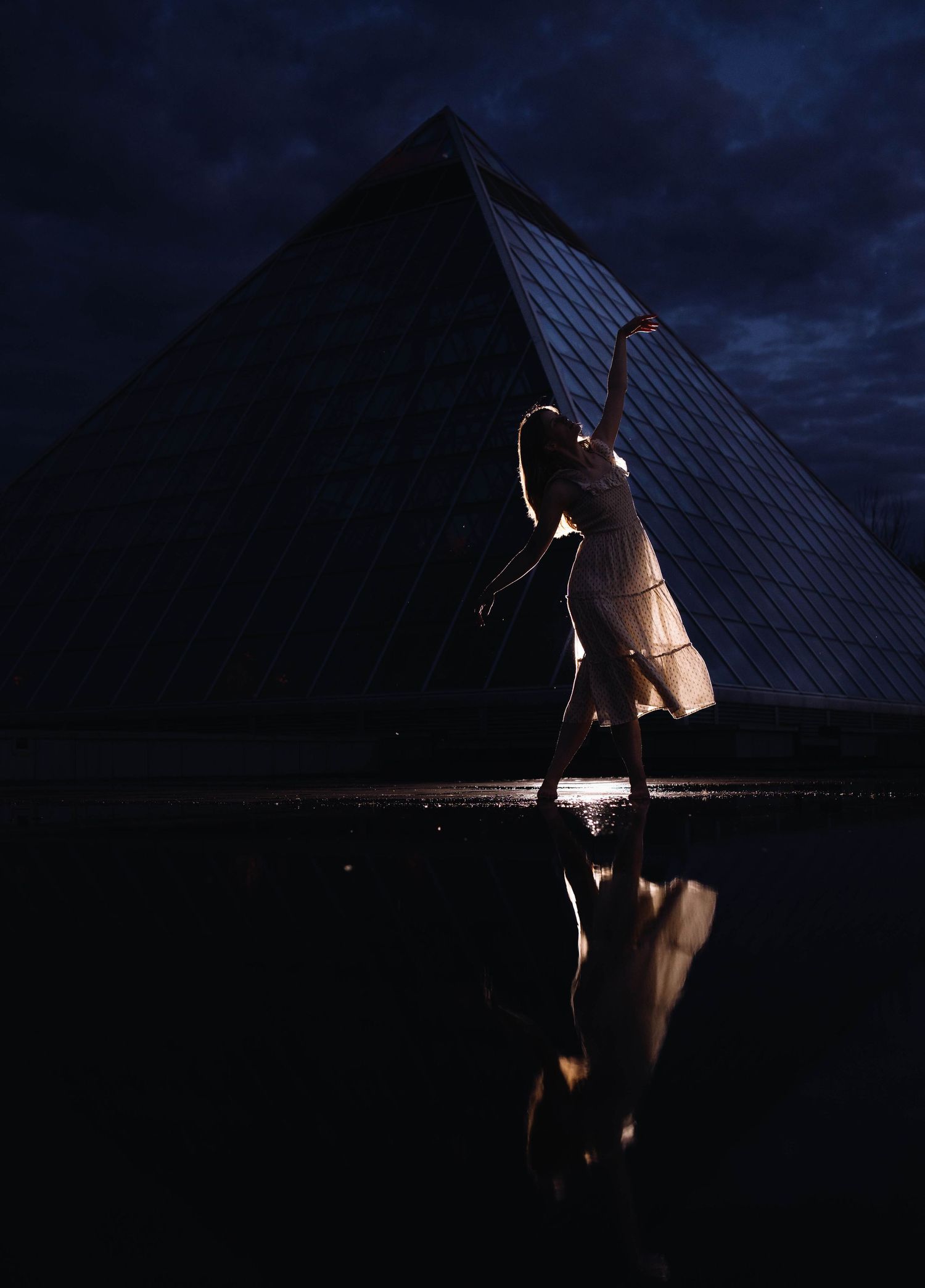 Silhouetted figure against illuminated bridge architecture at night.