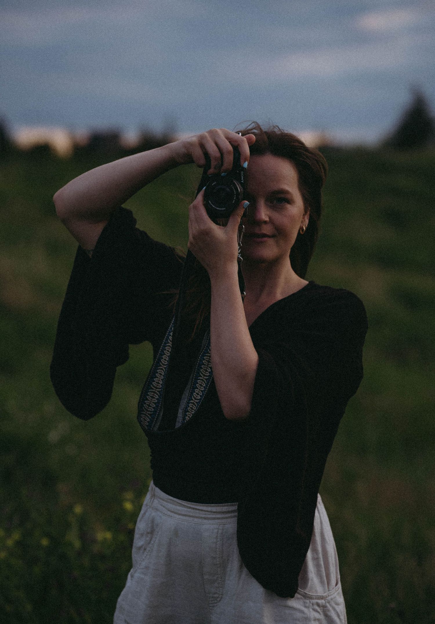 Photographer with vintage camera shooting in evening field.