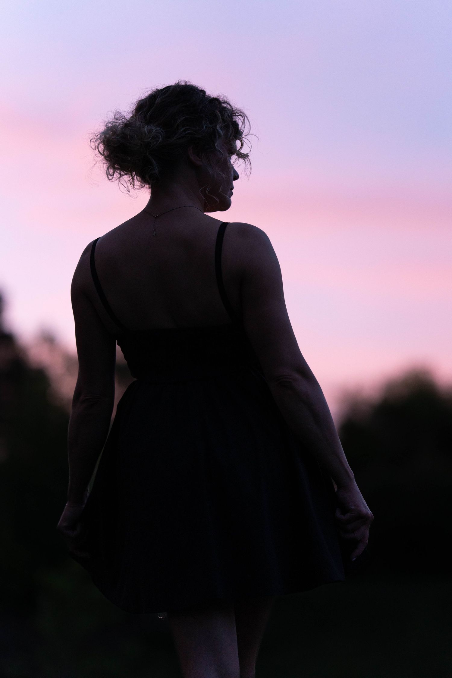 Silhouette dancing against purple sunset sky creating artistic outdoor portrait.