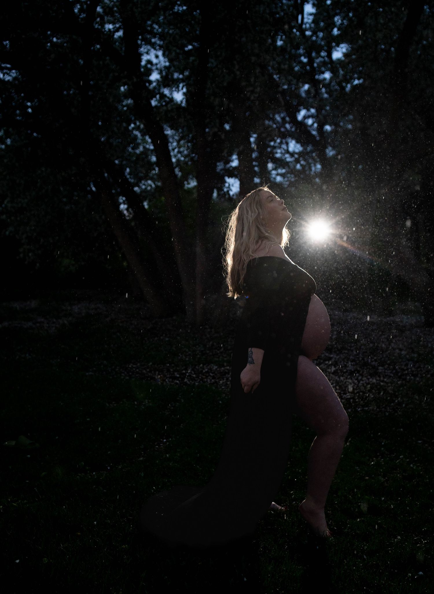 Nighttime outdoor portrait with starburst lighting effects through trees.