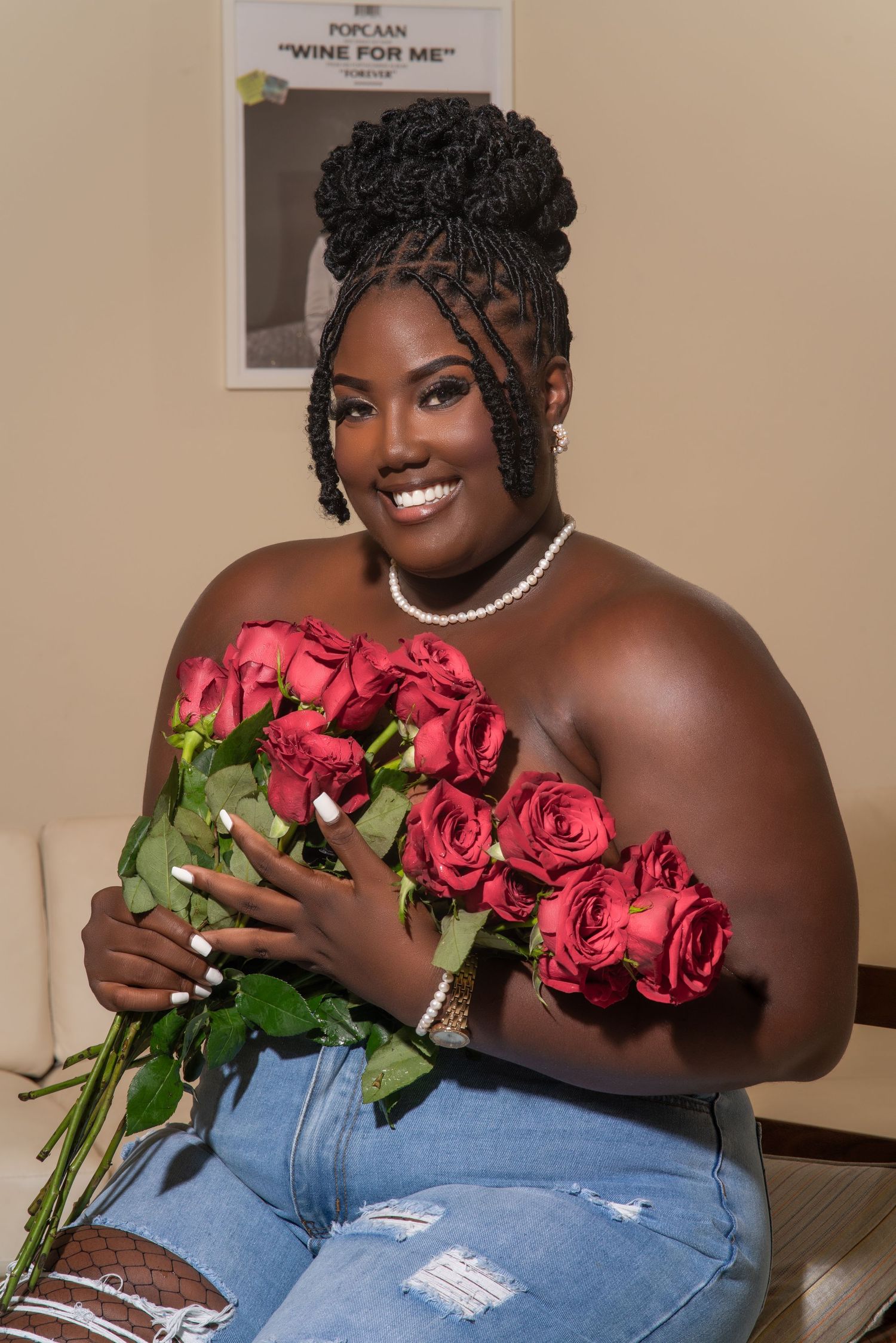 Young woman in ripped jeans poses with red roses in a romantic Valentine's Day themed photo.