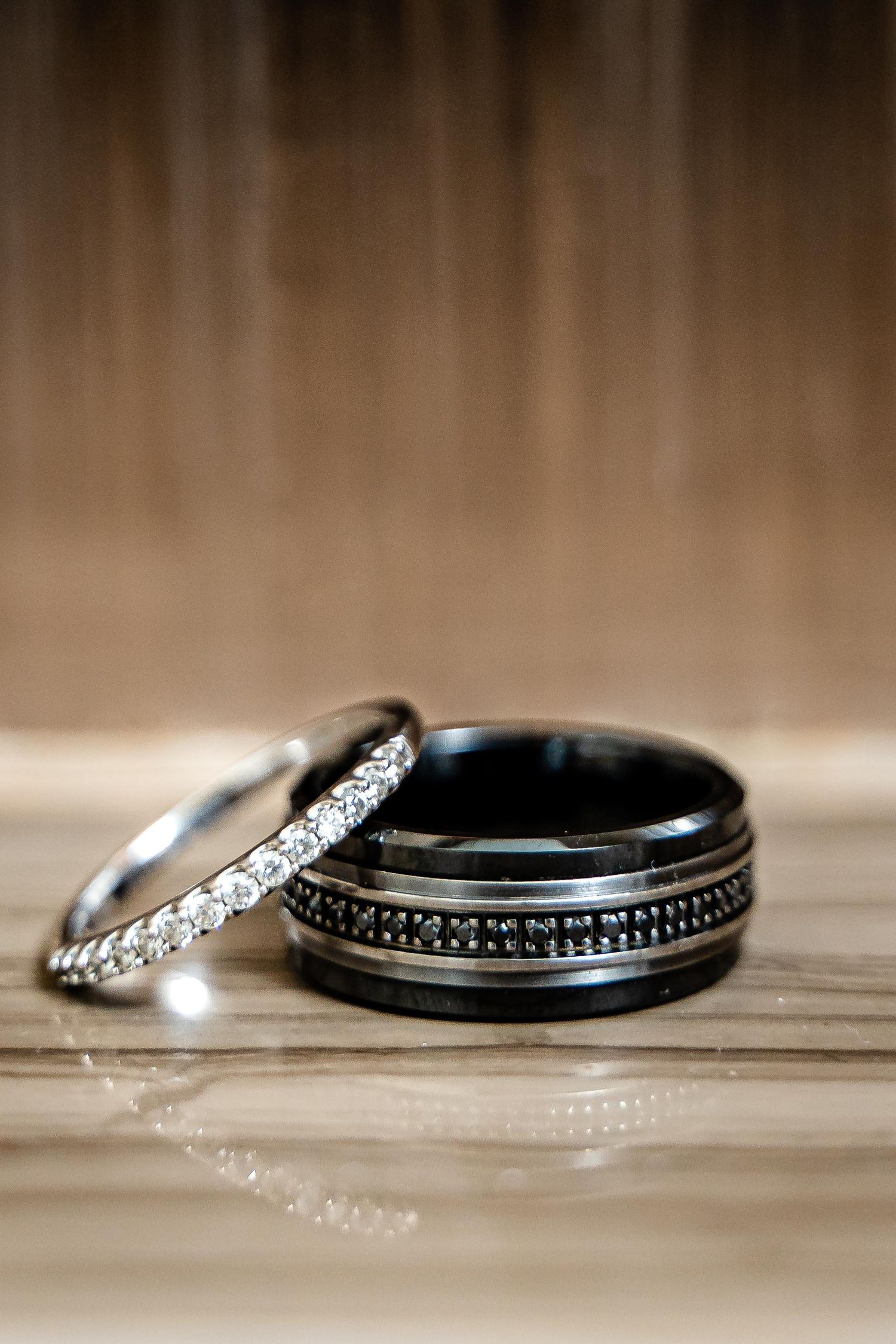 Wedding rings in black and white sitting on a wooden surface with shallow depth of field creating an artistic composition.