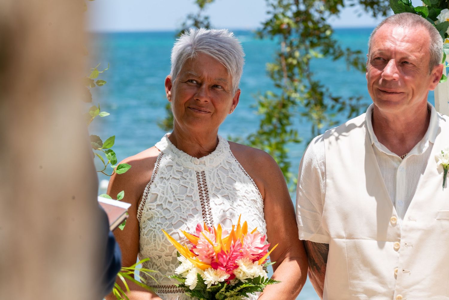 A happy couple shares a joyful moment at their outdoor beach wedding celebration on a sunny day.