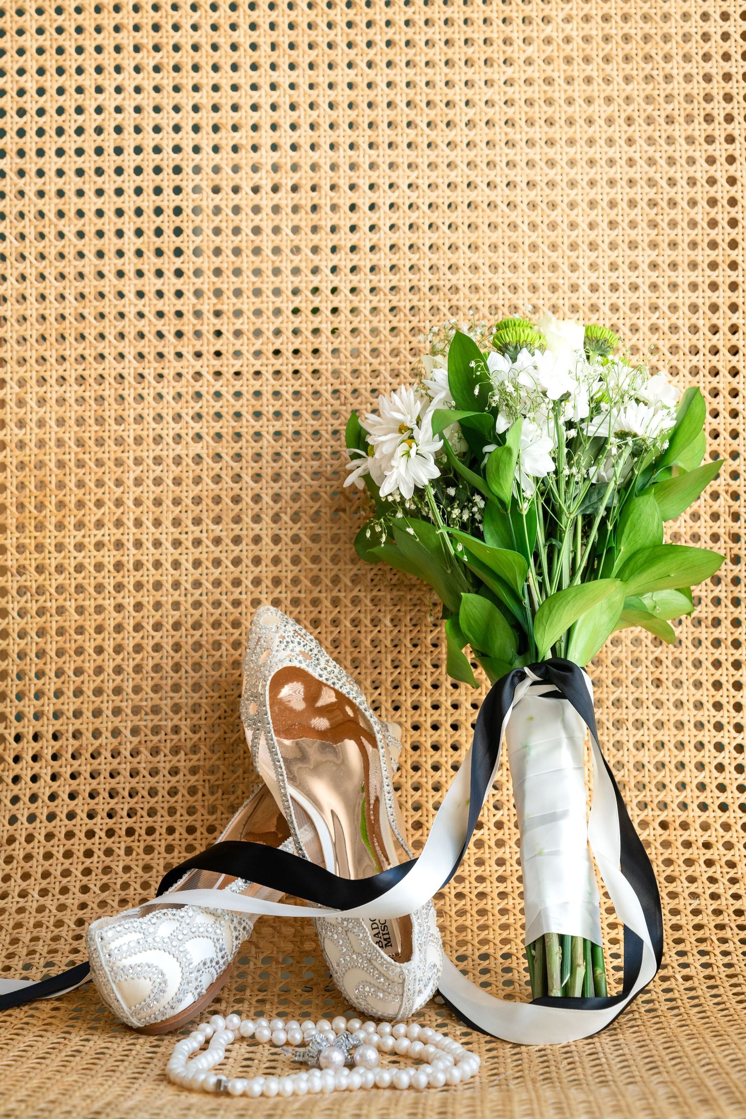 White ceramic cat planter with lily of the valley flowers arranged in sequence against a woven rattan backdrop.