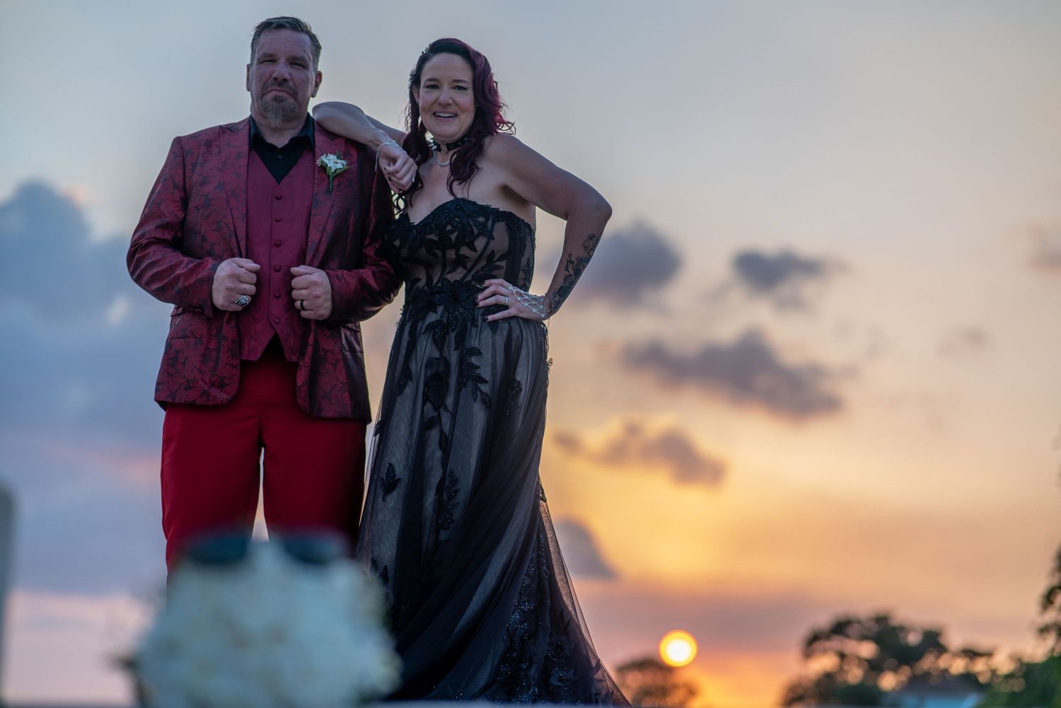 Two people pose together at sunset on a beach during a romantic photoshoot session.