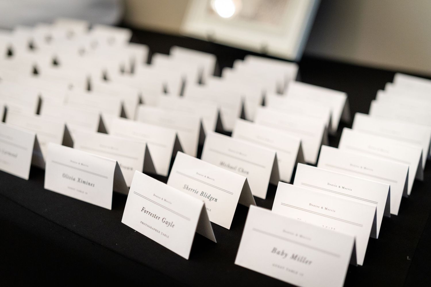 White wedding place cards arranged in rows on a dark surface for guest seating arrangements.