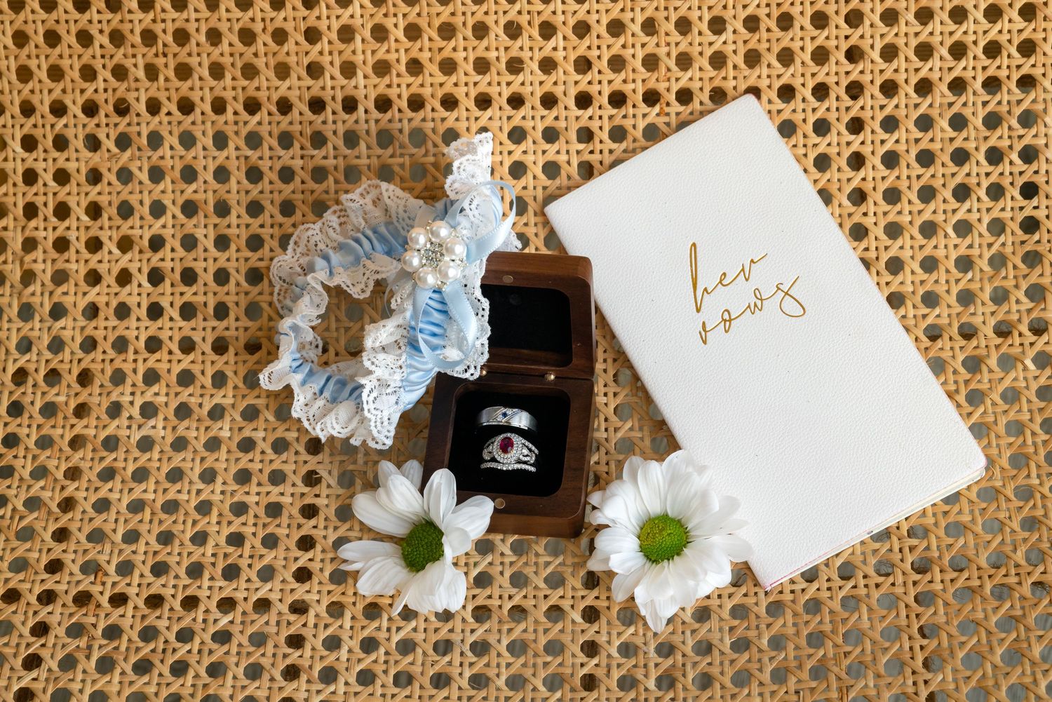 Place cards and light blue flowers arranged on a rattan textured surface with black candle holders.