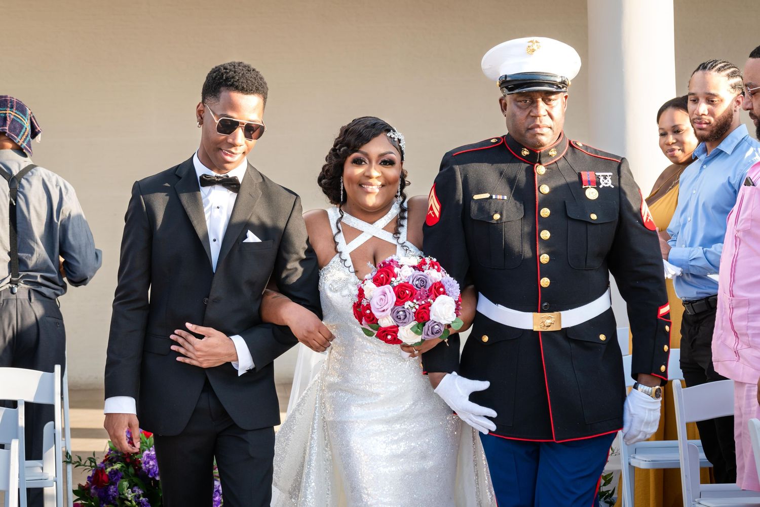 Military service members and guests gather at a formal event, standing in line wearing dress uniforms and formal attire.