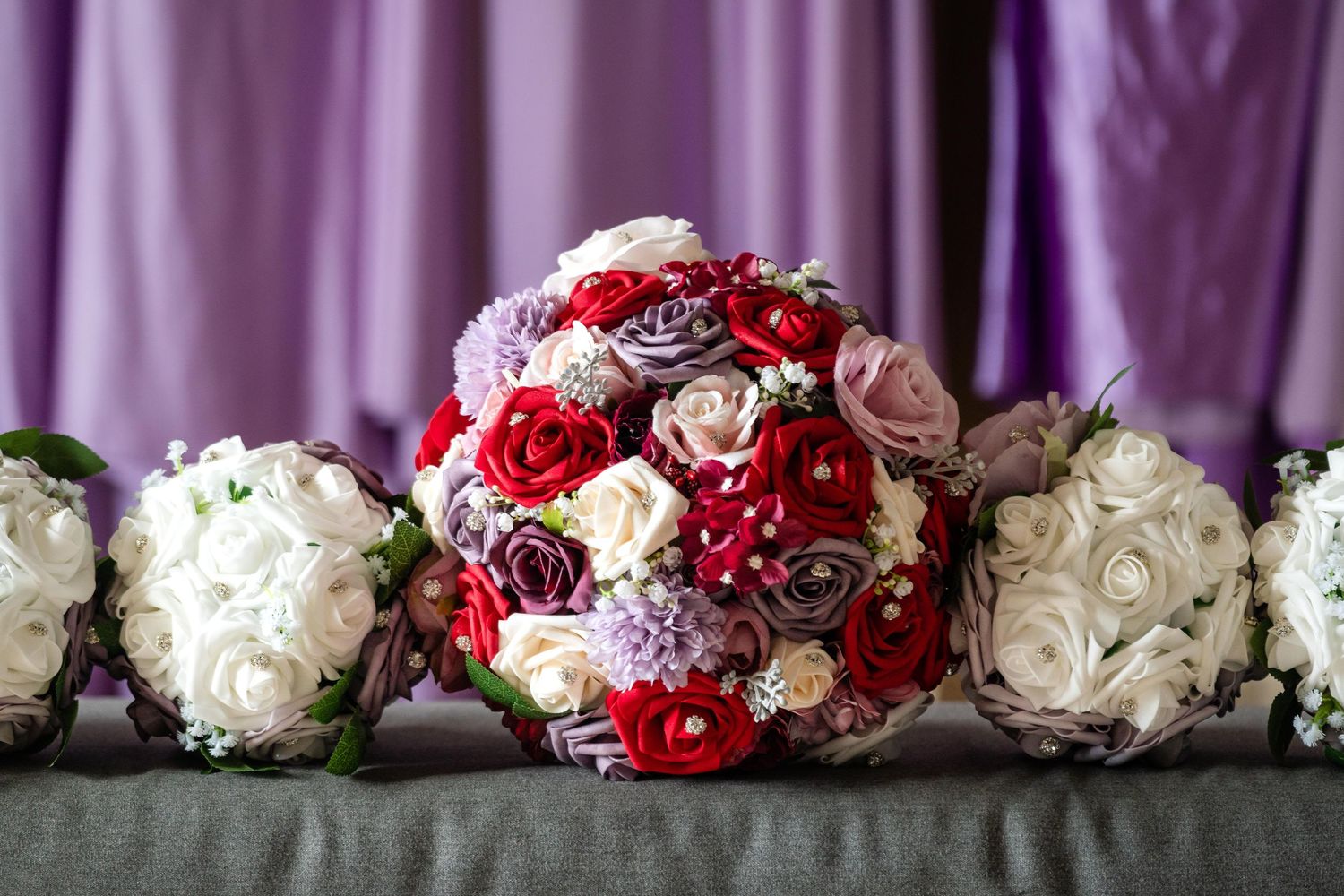 A stunning wedding bouquet arrangement with red and white roses sits elegantly against a dark background.