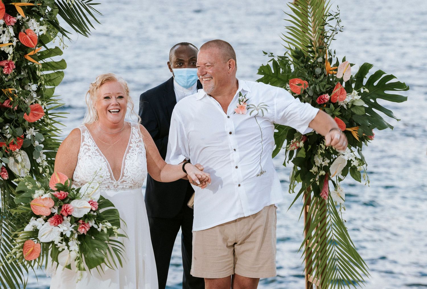 A beachside wedding celebration with tropical decor and floral arrangements by the ocean.