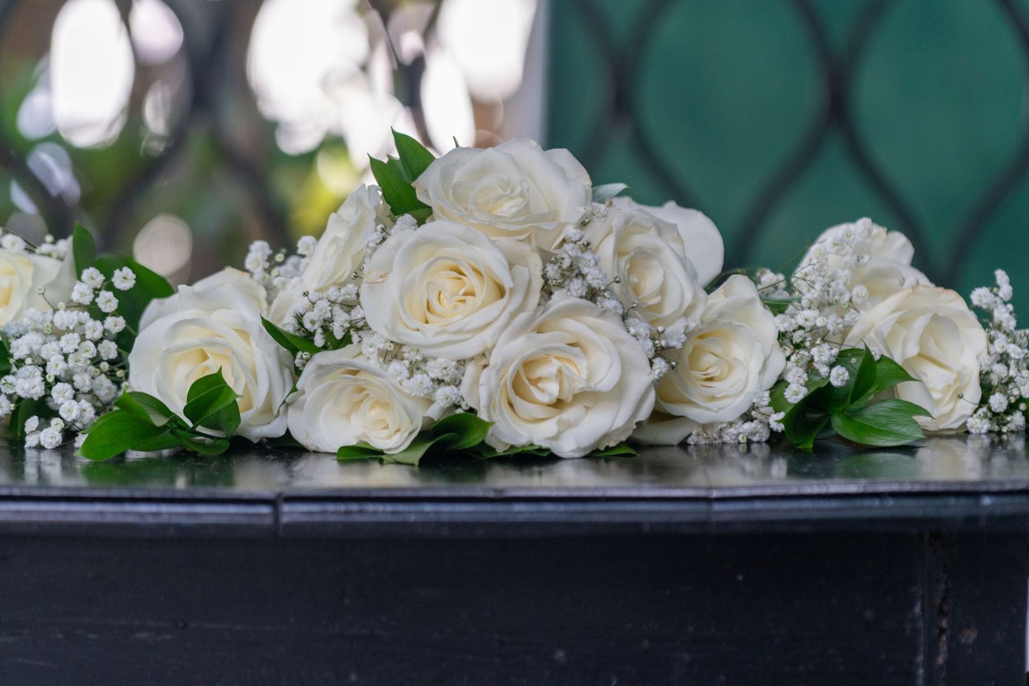 White roses and greenery garlands create an elegant floral border display against a dark backdrop.