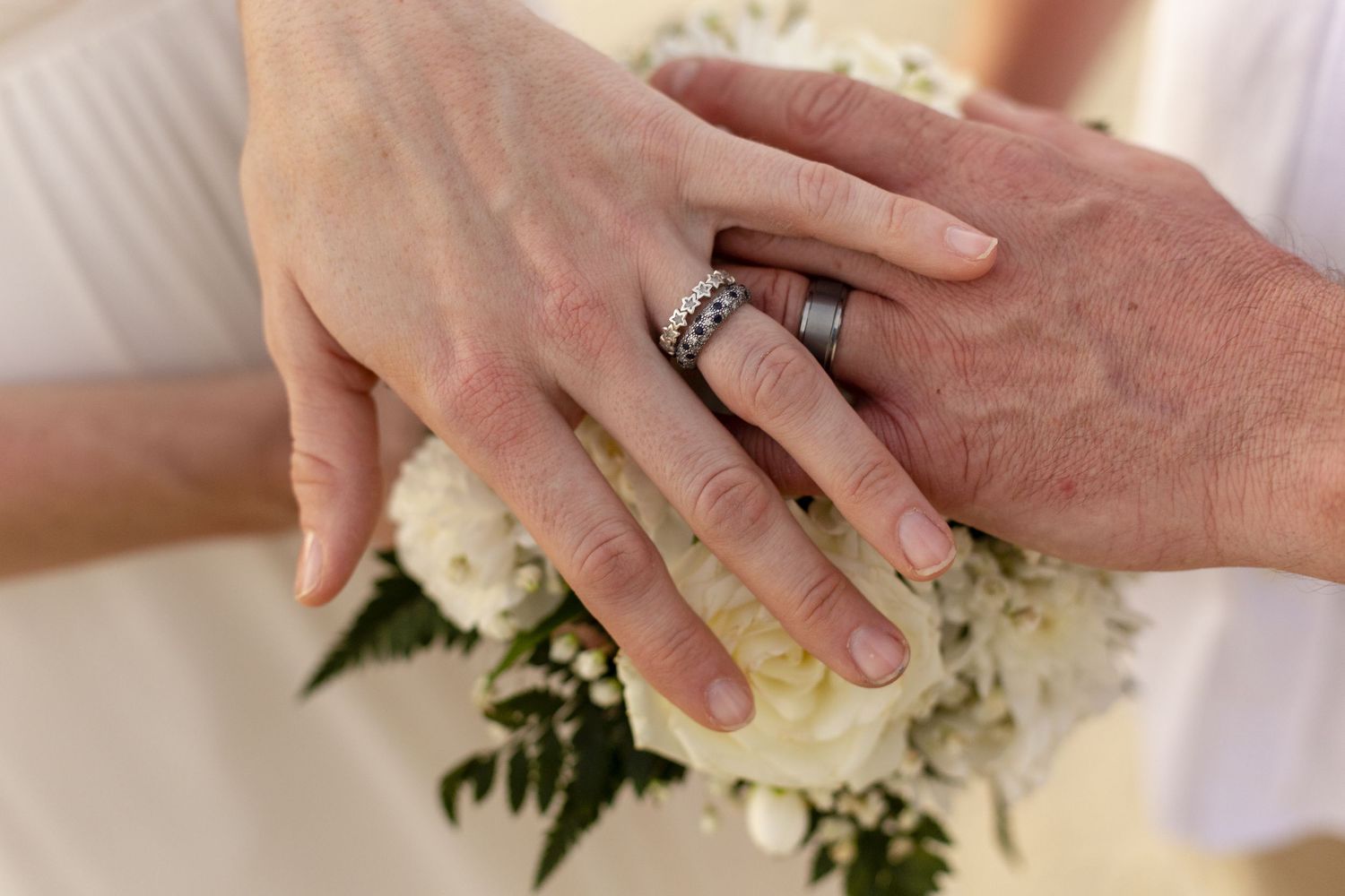 Multiple pairs of hands are shown handling and working with white floral arrangements together.