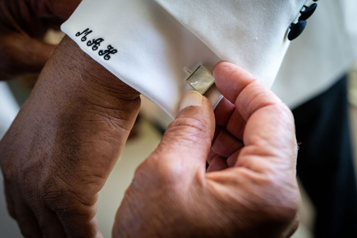 Close-up view of hands writing with pen on white paper with elegant calligraphy strokes.