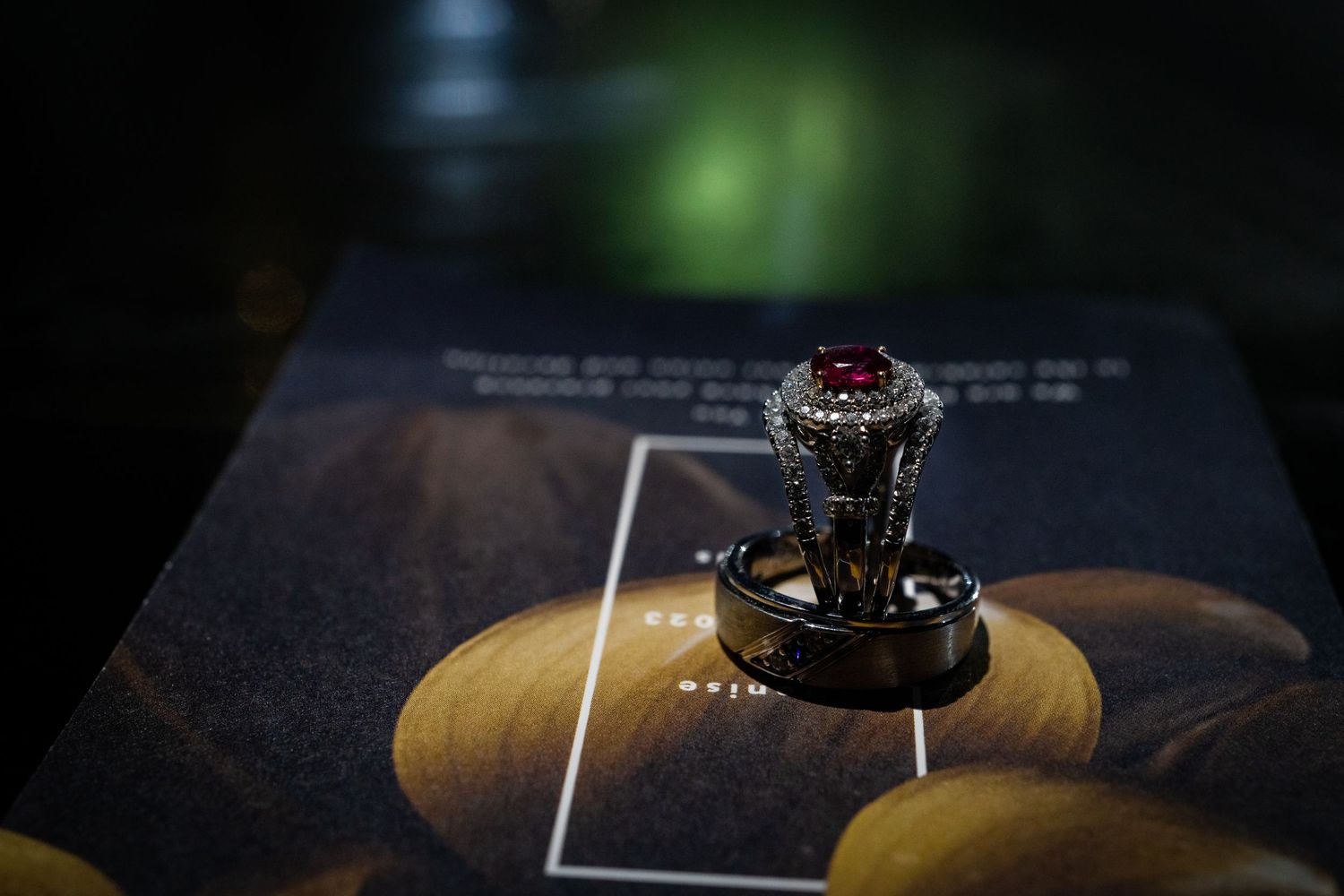 Close-up of fine jewelry pieces arranged on a dark surface with dramatic lighting and reflections.