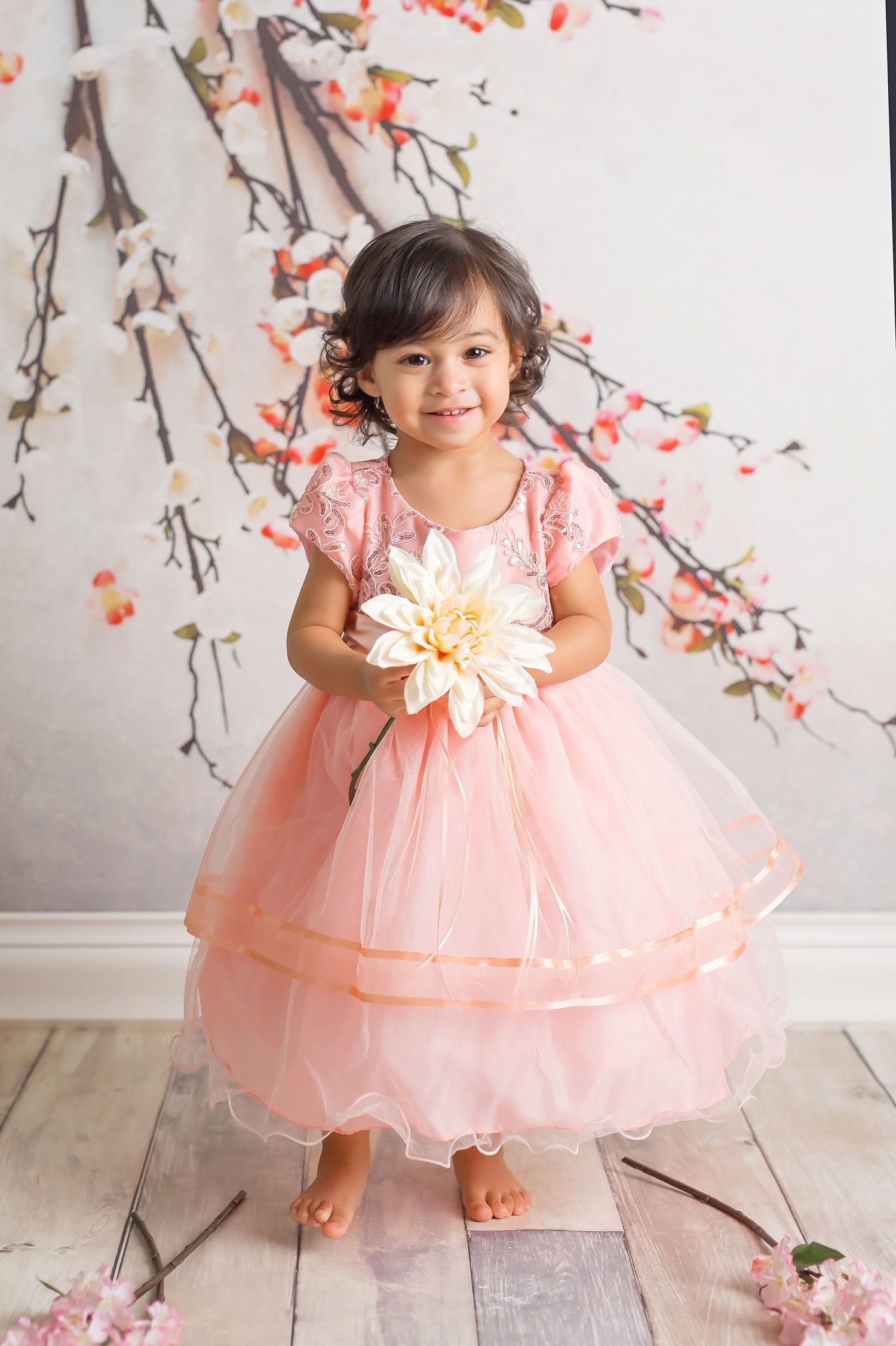 San Diego newborn photographer captures A young child in a pink tulle party dress poses against a floral backdrop.