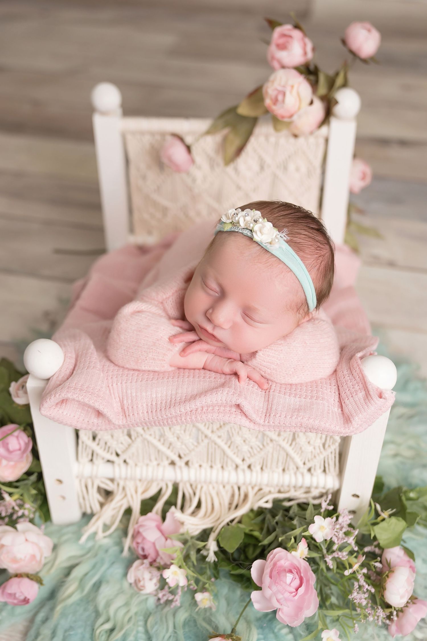 Newborn sleeping on white vintage bed with pink roses and delicate decorations. San Diego Newborn Photographer