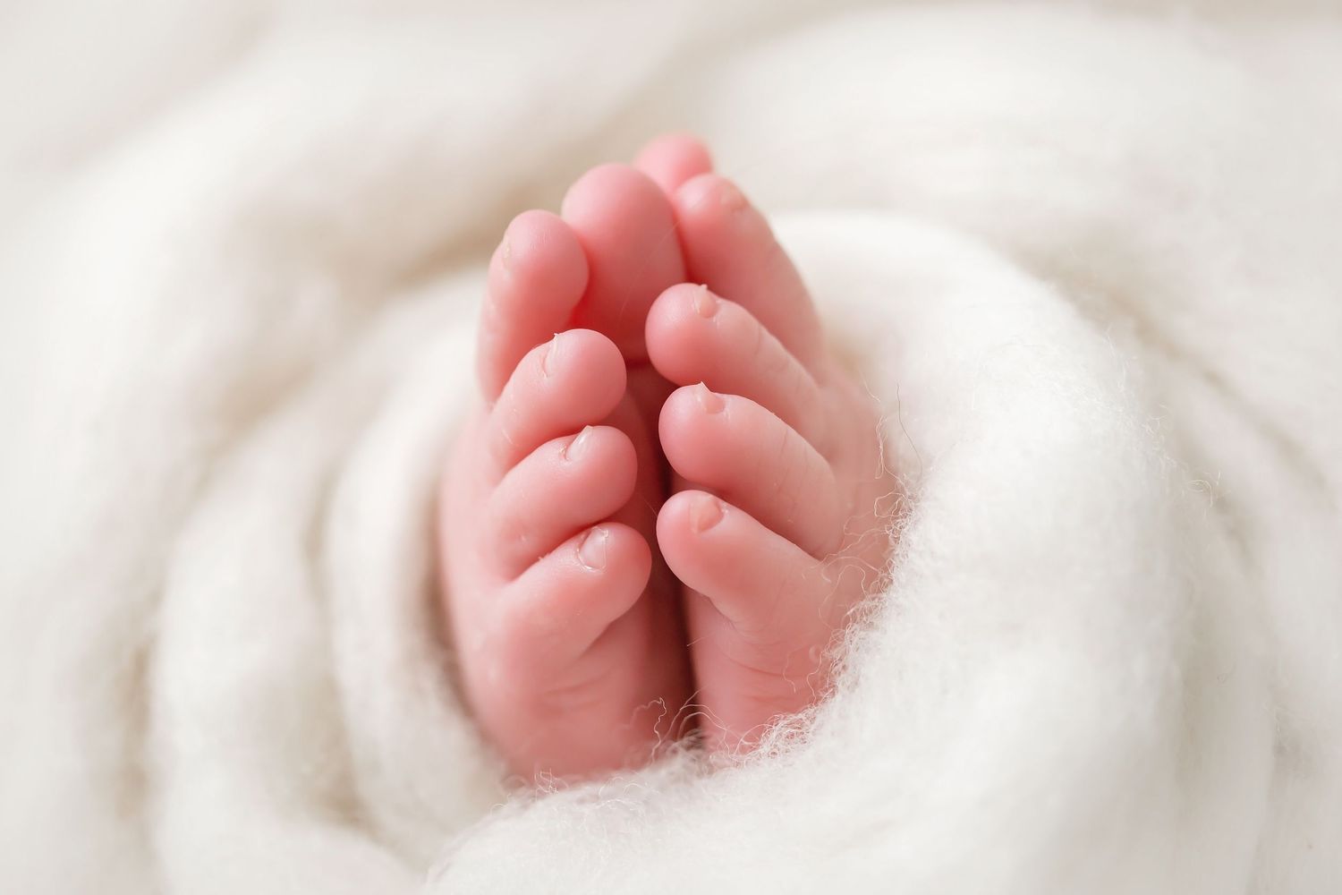 San Diego newborn photographer captures Close-up shots of tiny baby feet wrapped in soft white blankets.