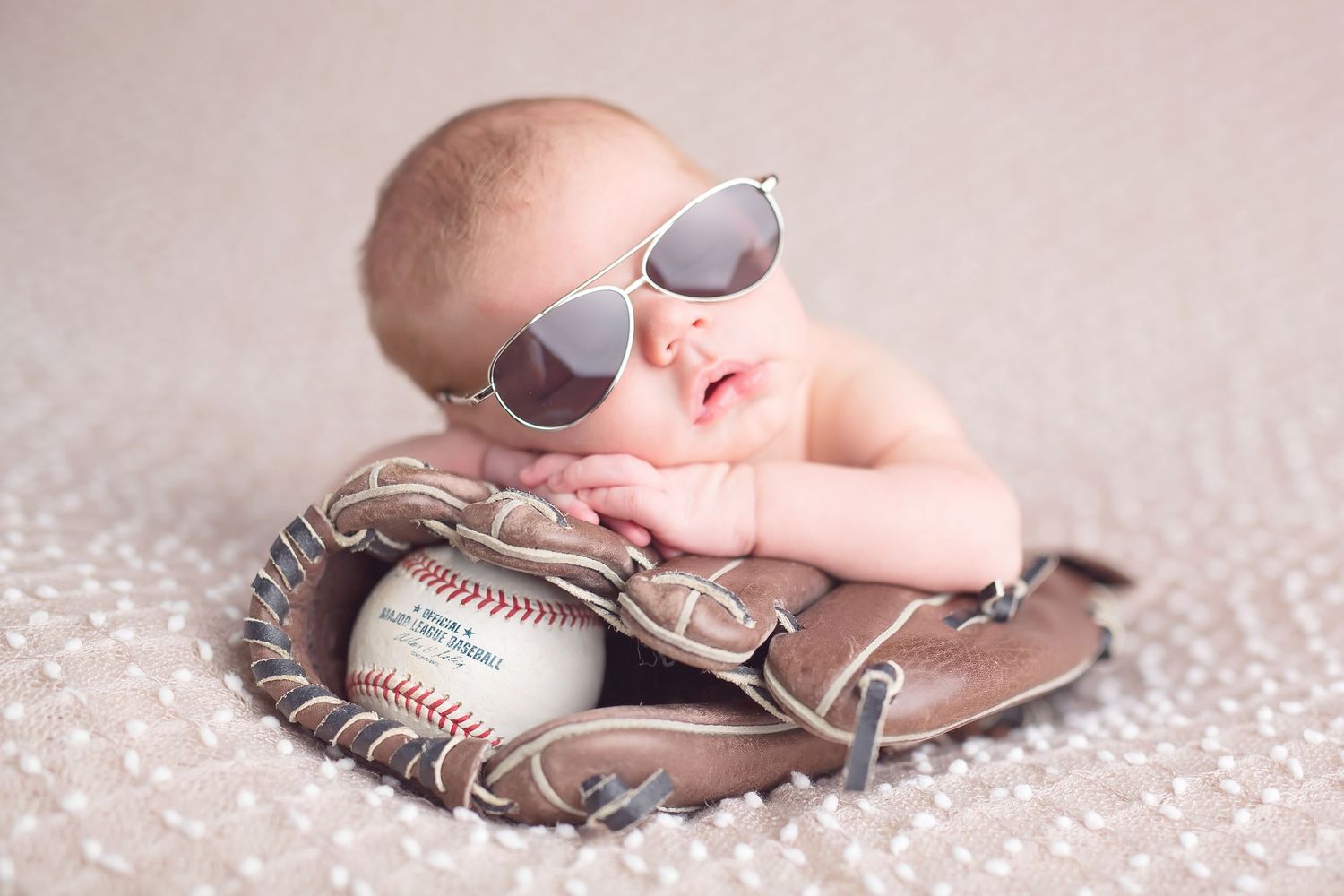 Newborn baby wearing sunglasses posed with baseball and leather glove. San Diego Newborn Photographer