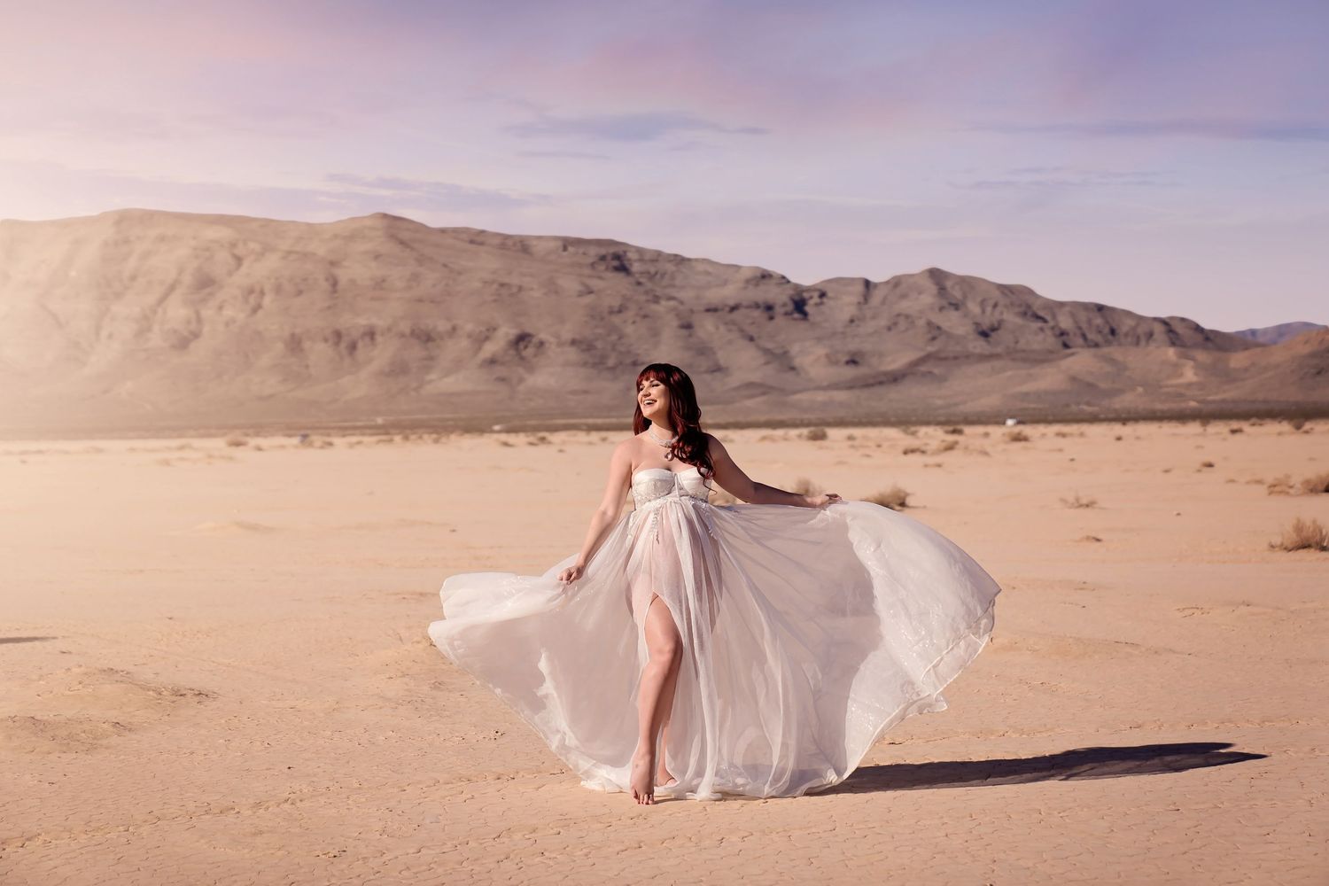 Maternity Photos as A white dress creates an ethereal effect against the desert mountains and sky. San Diego Maternity Photographer