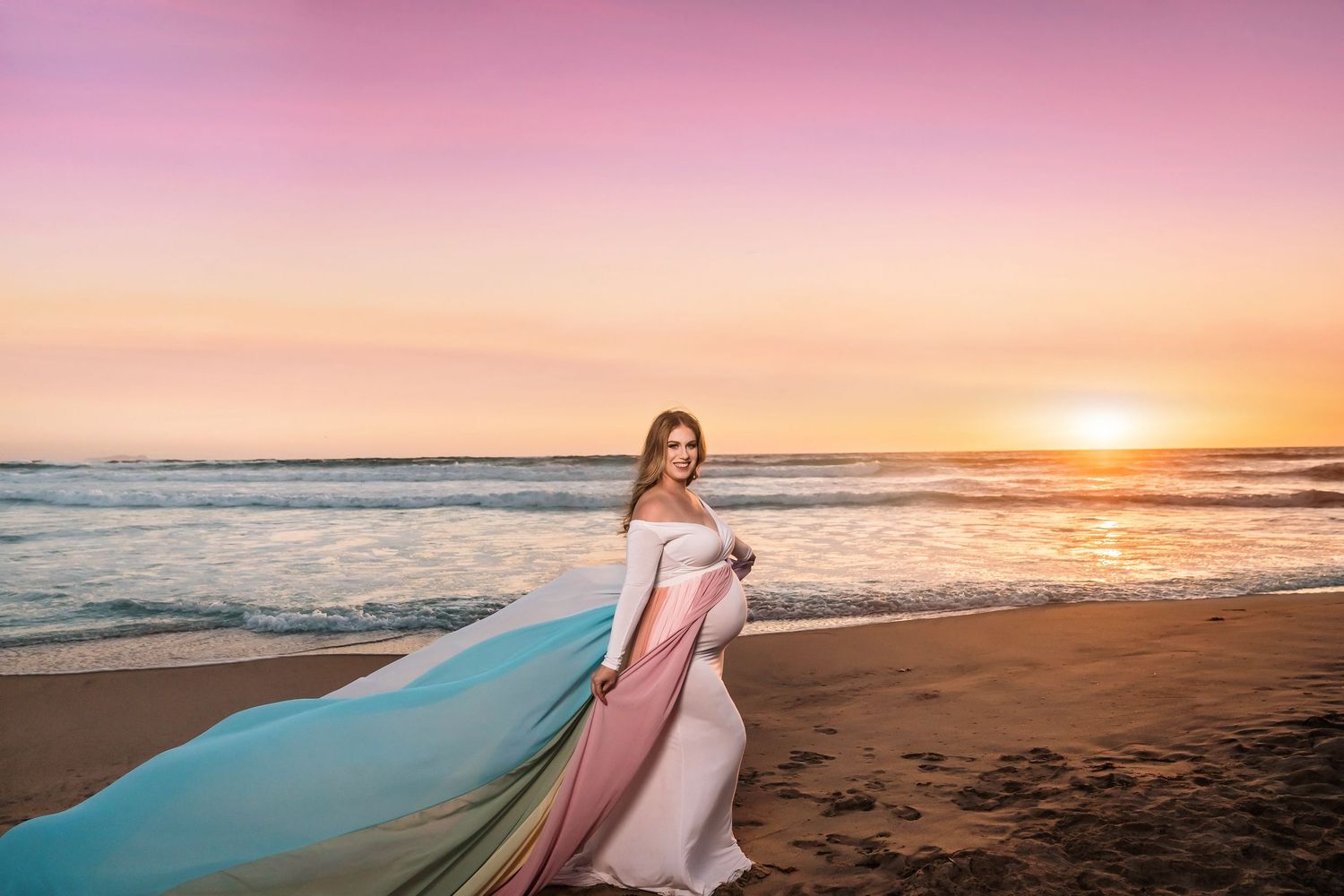 Dreamy beach photoshoot featuring rainbow flowing dresses at golden hour. San Diego Maternity Photographer
