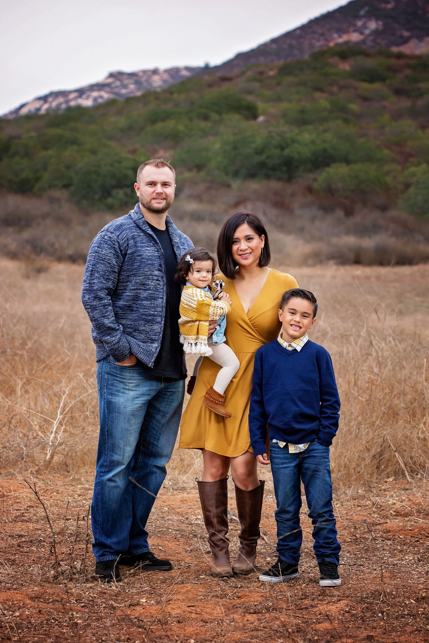 Family portrait in casual wear against a mountain backdrop during golden hour
