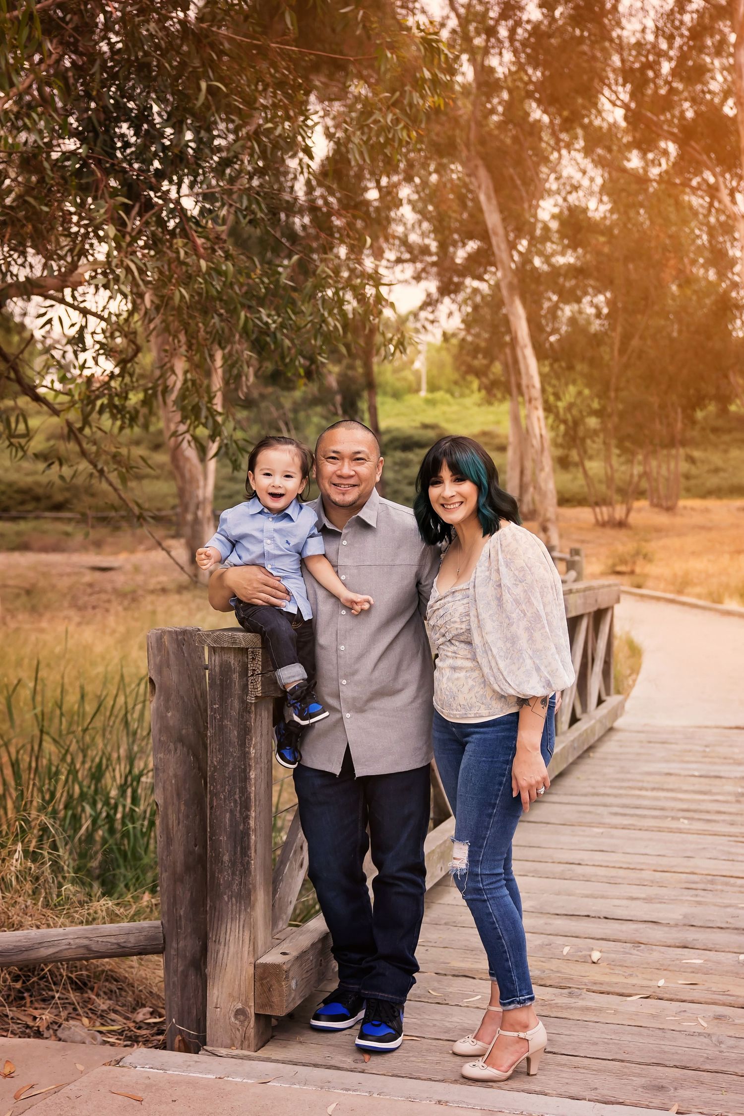 Family standing together on a wooden boardwalk during golden hour with warm sunset light